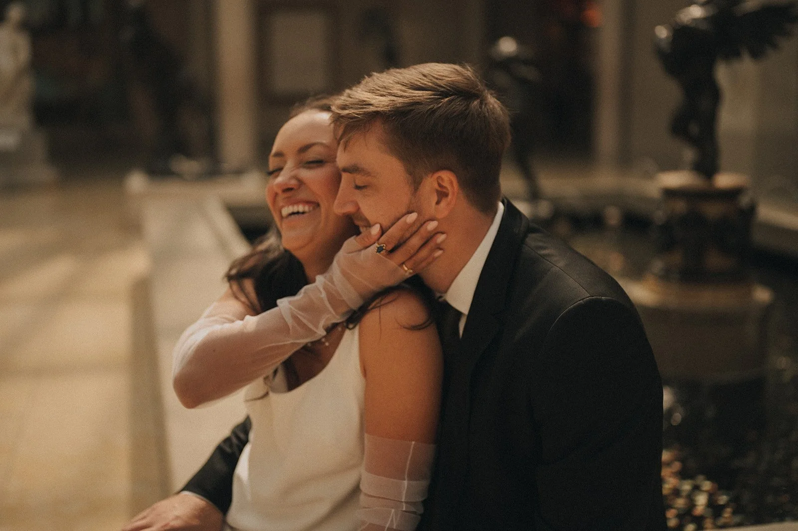 A candid close-up of Kayla laughing and holding Zach’s face during their elopement portraits at the Met.