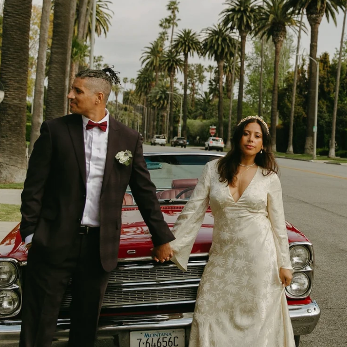 Couple with a vintage red convertible on a palm-lined LA street