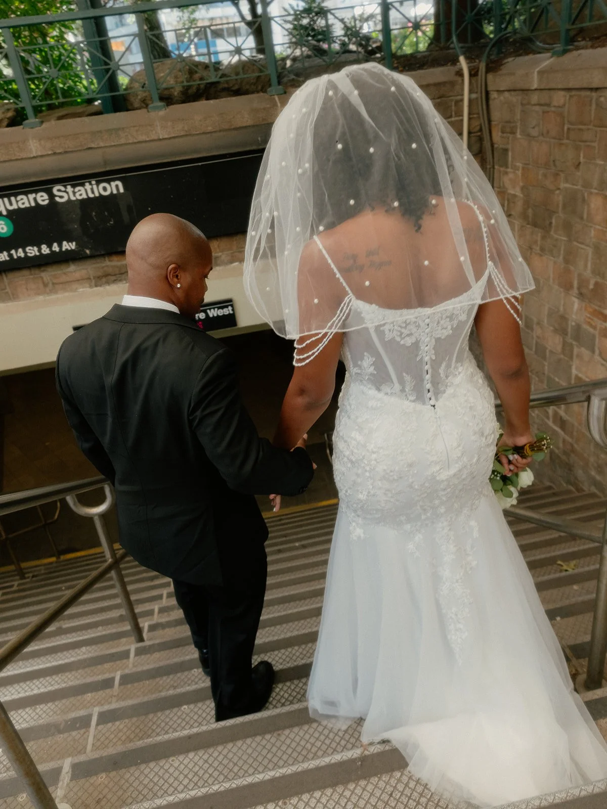 Bride and groom descending the stairs into a subway station in New York City after their Cakewalk elopement.