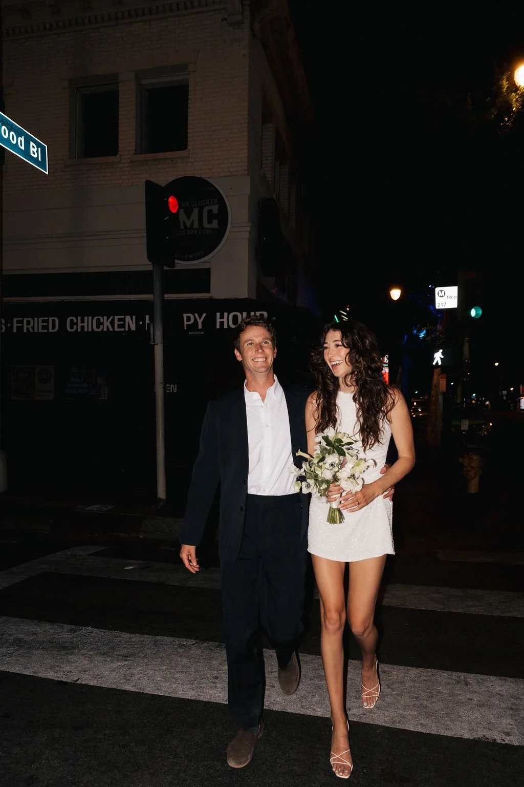 Couple walking on Hollywood Blvd at night in wedding attire.