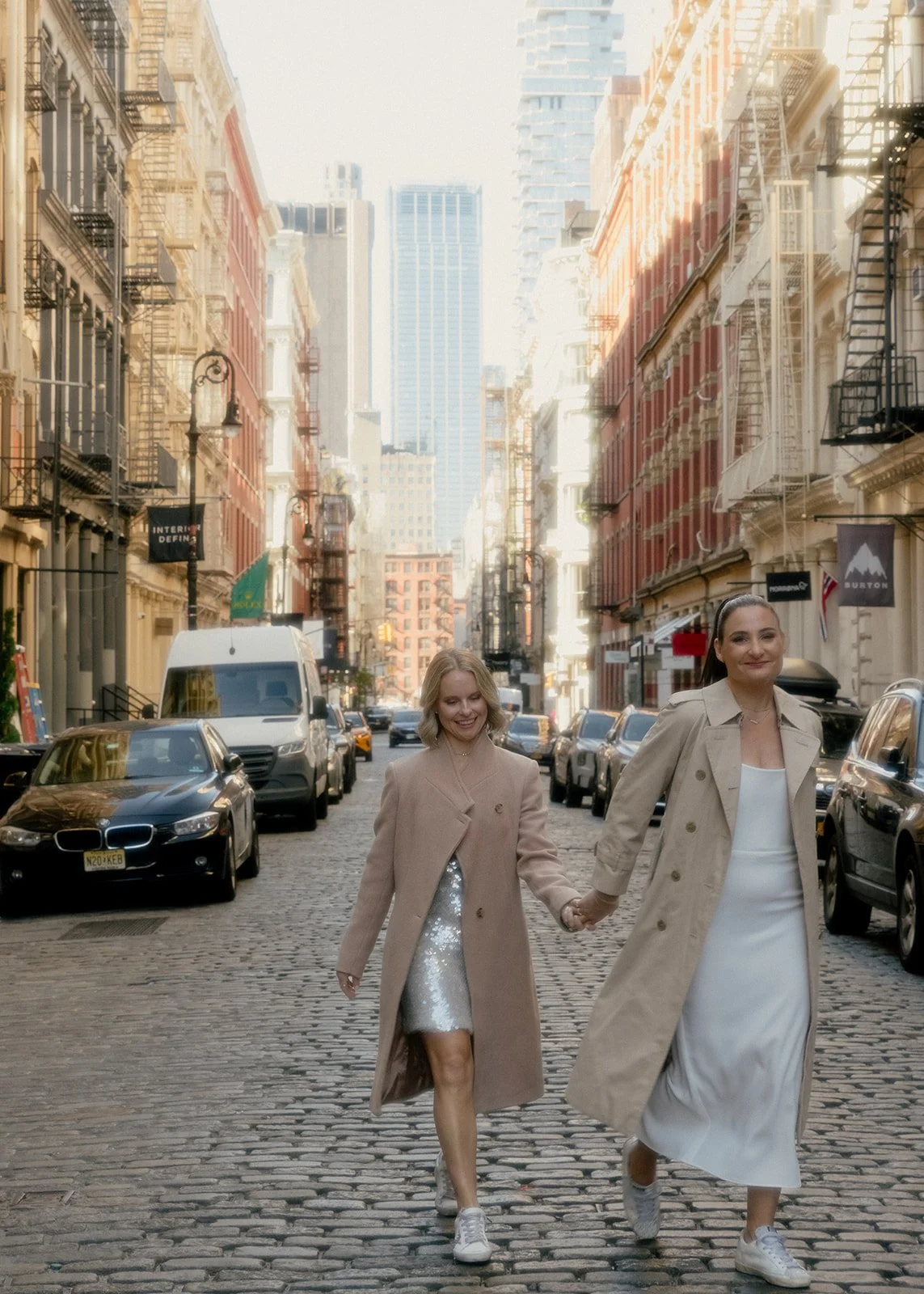 LGBT brides walking down the cobblestone street in Manhattan surrounded by buildings.