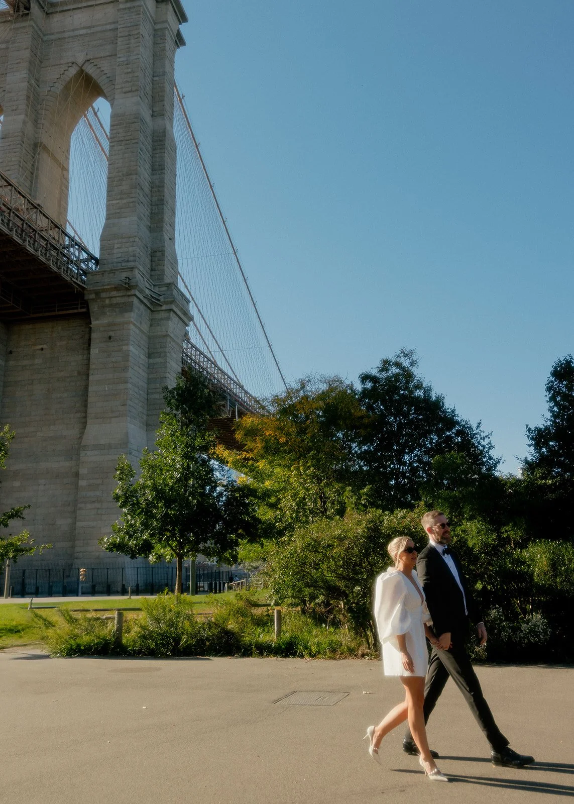 Bride and groom walking out from under the Brooklyn Bridge after their Cakewalk elopement.