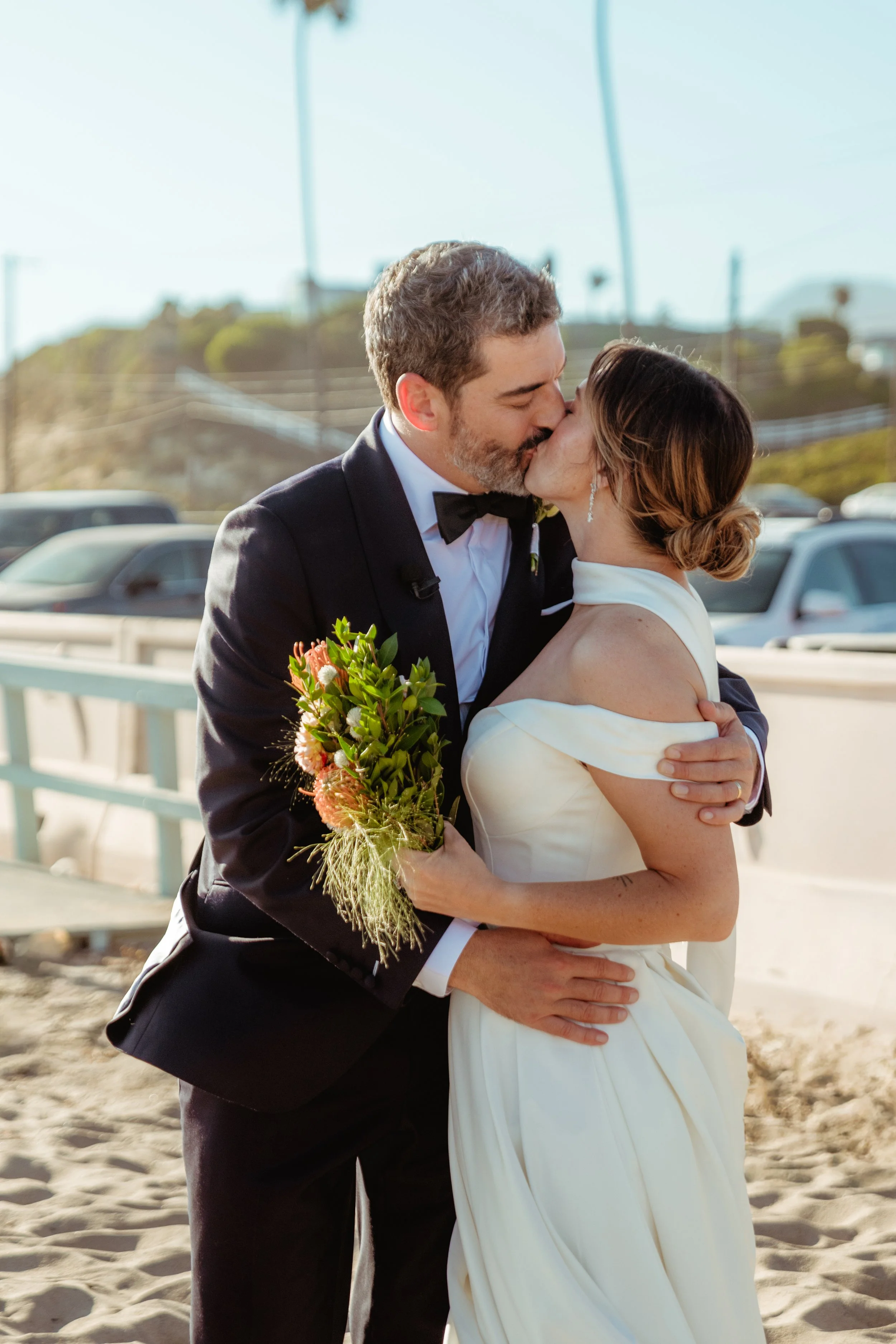 Bride and groom kissing on the sand at Zuma Beach after their Cakewalk micro wedding.