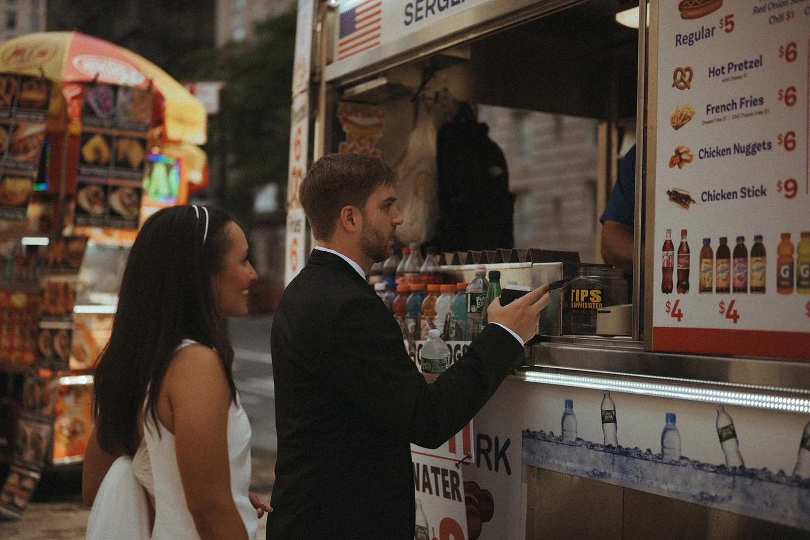 Bride and groom ordering food from a food stand across from the Met Museum after their Cakewalk elopement.