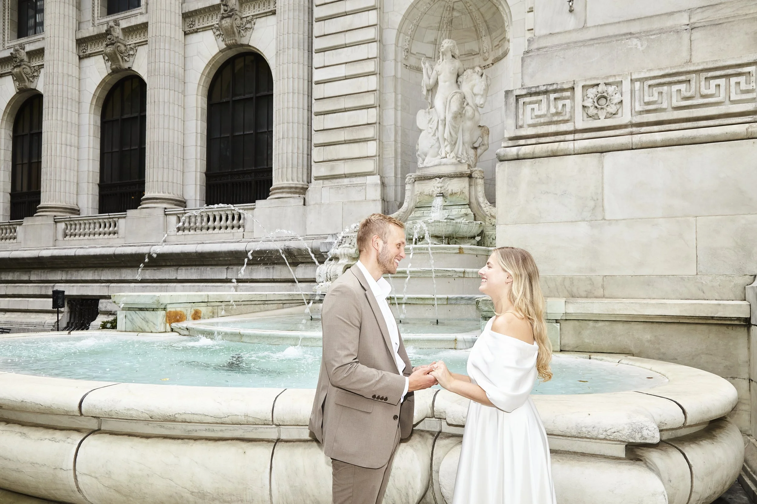 Bride and groom holding hands in front of the fount at Bryant Park after their Cakewalk elopement.