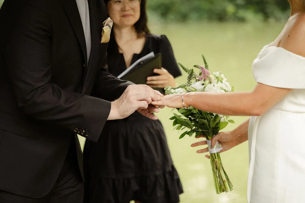 Chloe and Sam outdoors during their Wagner Cove Cakewalk NYC elopement, bride holding a bouquet of white flowers.