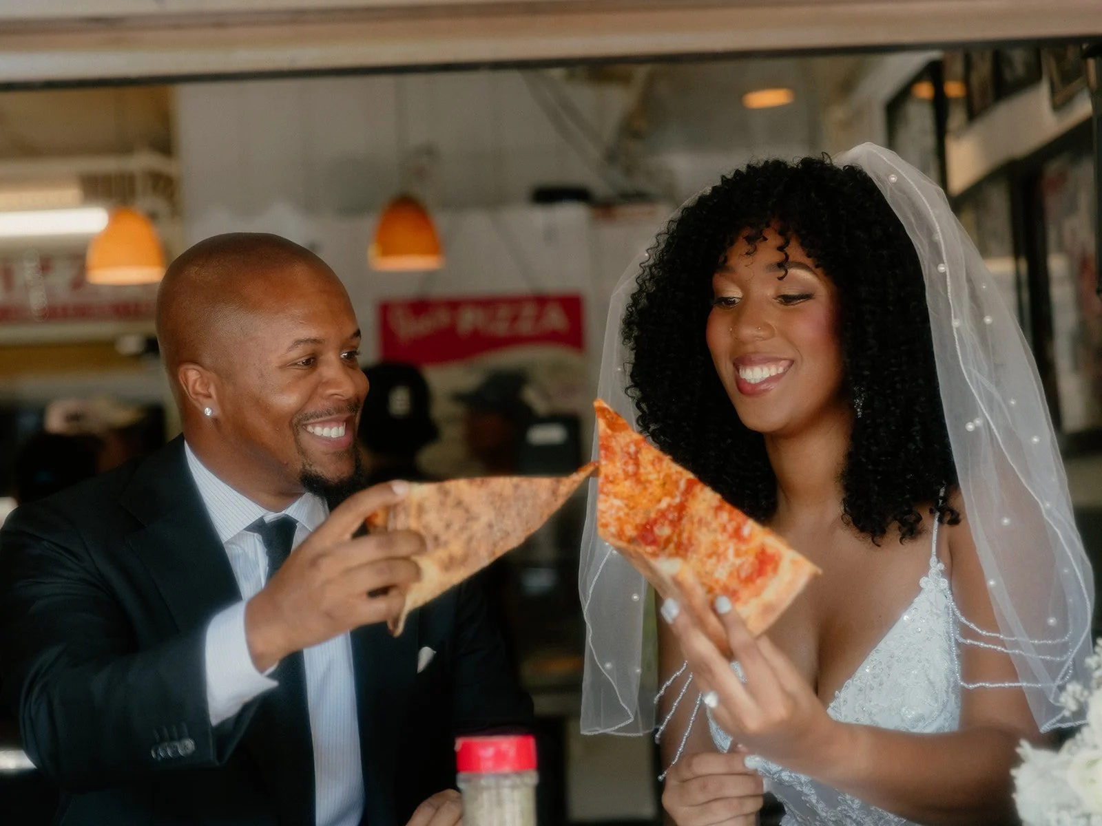 Bride and groom smiling and sharing slices of pizza at Joe's Pizza in New York City after their Cakewalk elopement.