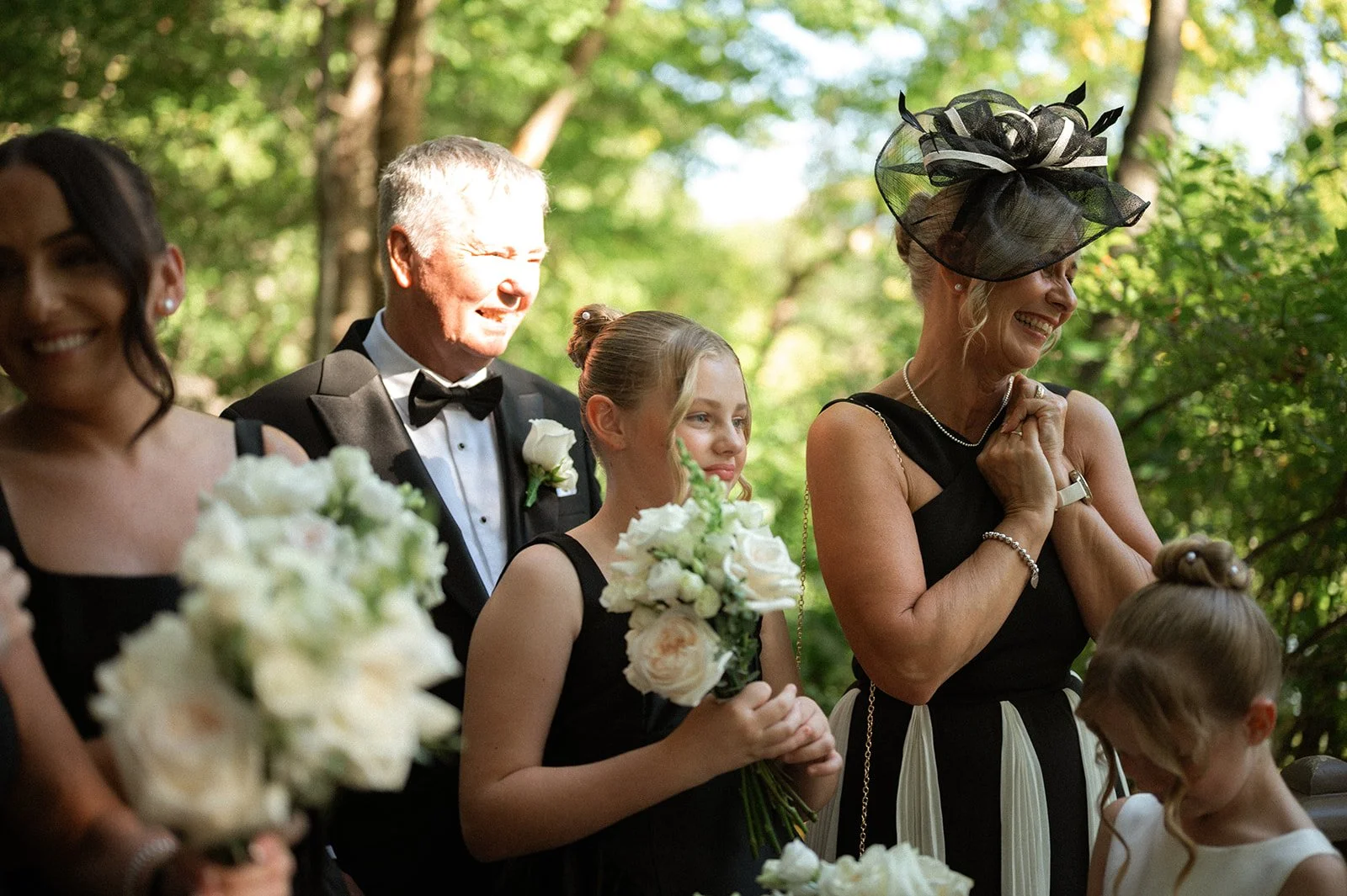 Wedding guests wearing black and white smiling and watching a micro wedding in Central Park, surrounded by greenery.