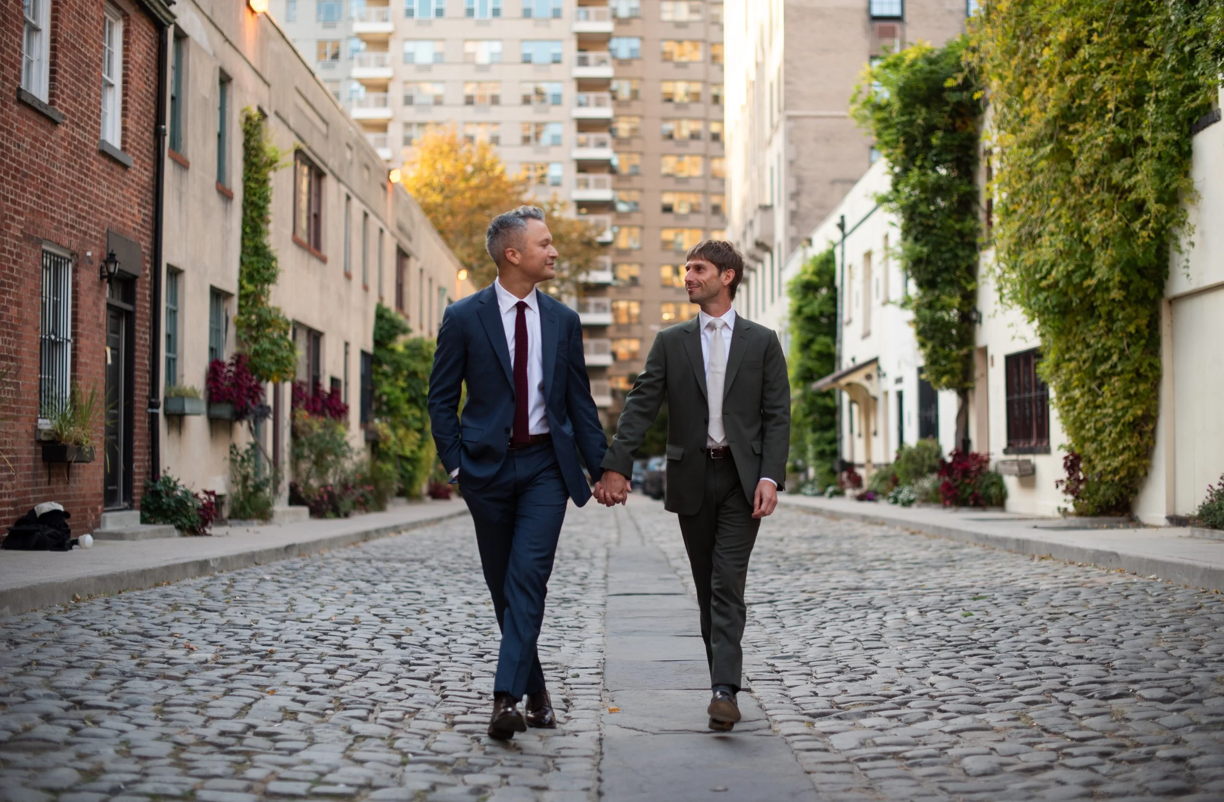 A gay LGBT couple holding hands as they walk though Washington Square Park where they just had an elopement wedding ceremony with Cakewalk