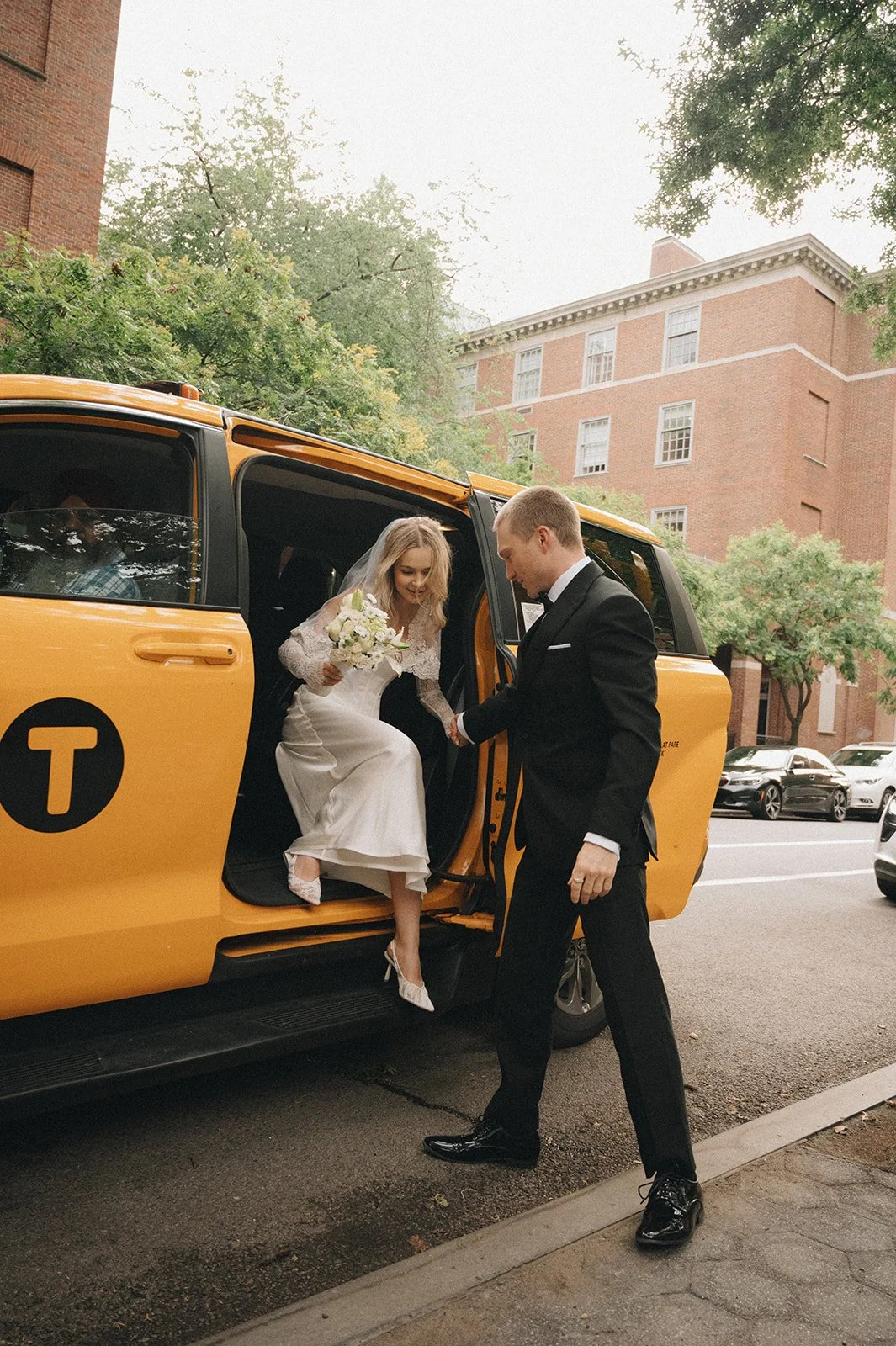 Couple exiting a taxi dressed in a wedding gown and tuxedo during their Cakewalk elopement.