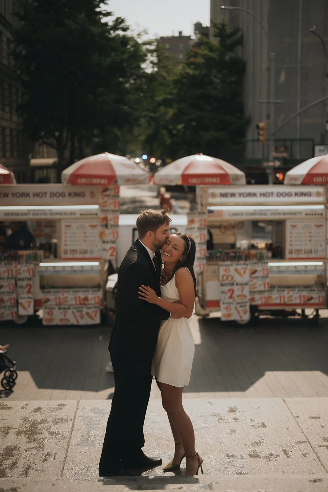Bride and groom embracing in front of food stands across from the Met Museum after their Cakewalk elopement.