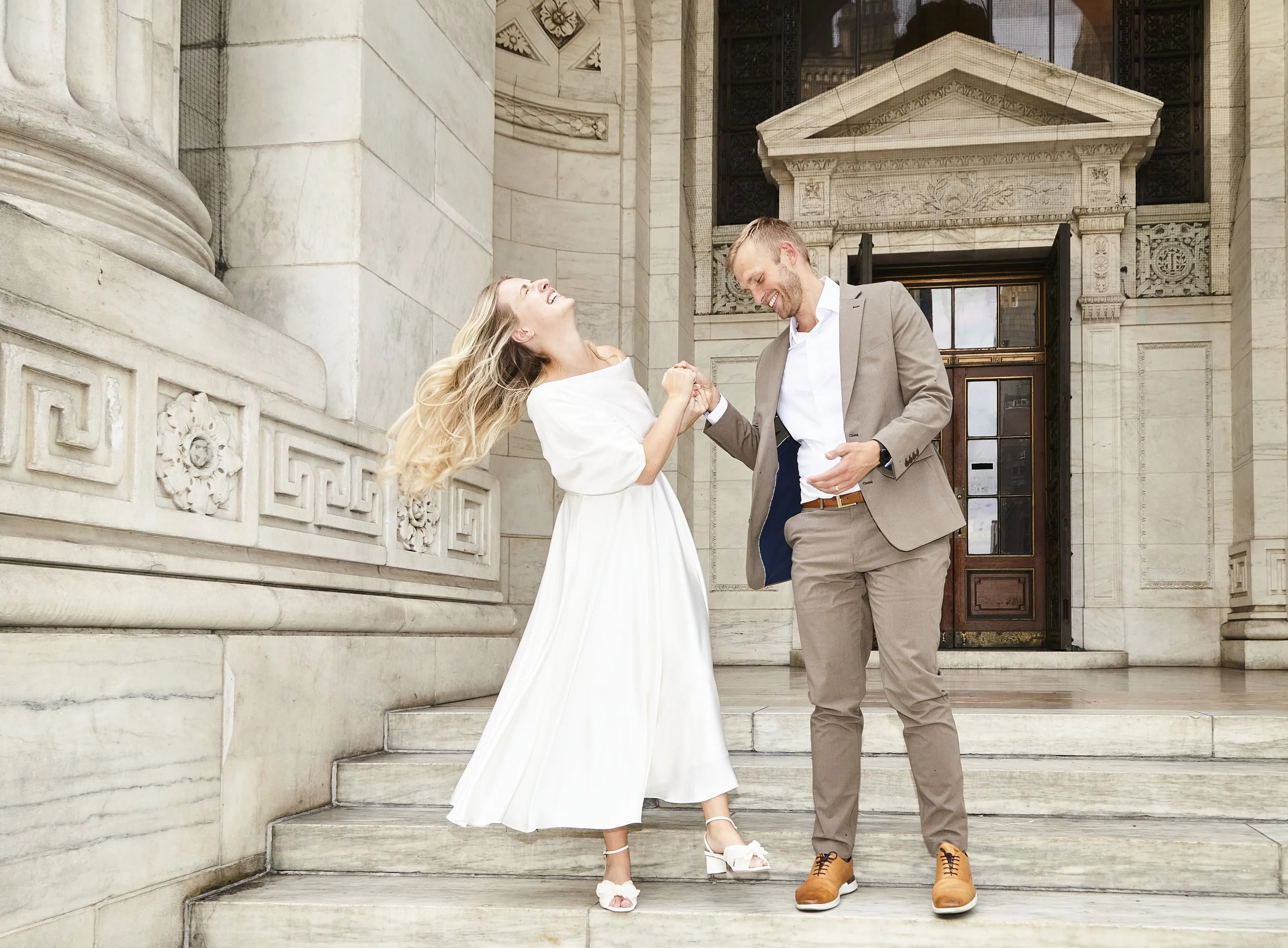 Bride and groom smiling and dancing on the stairs at Bryant Park after their Cakewalk elopement.