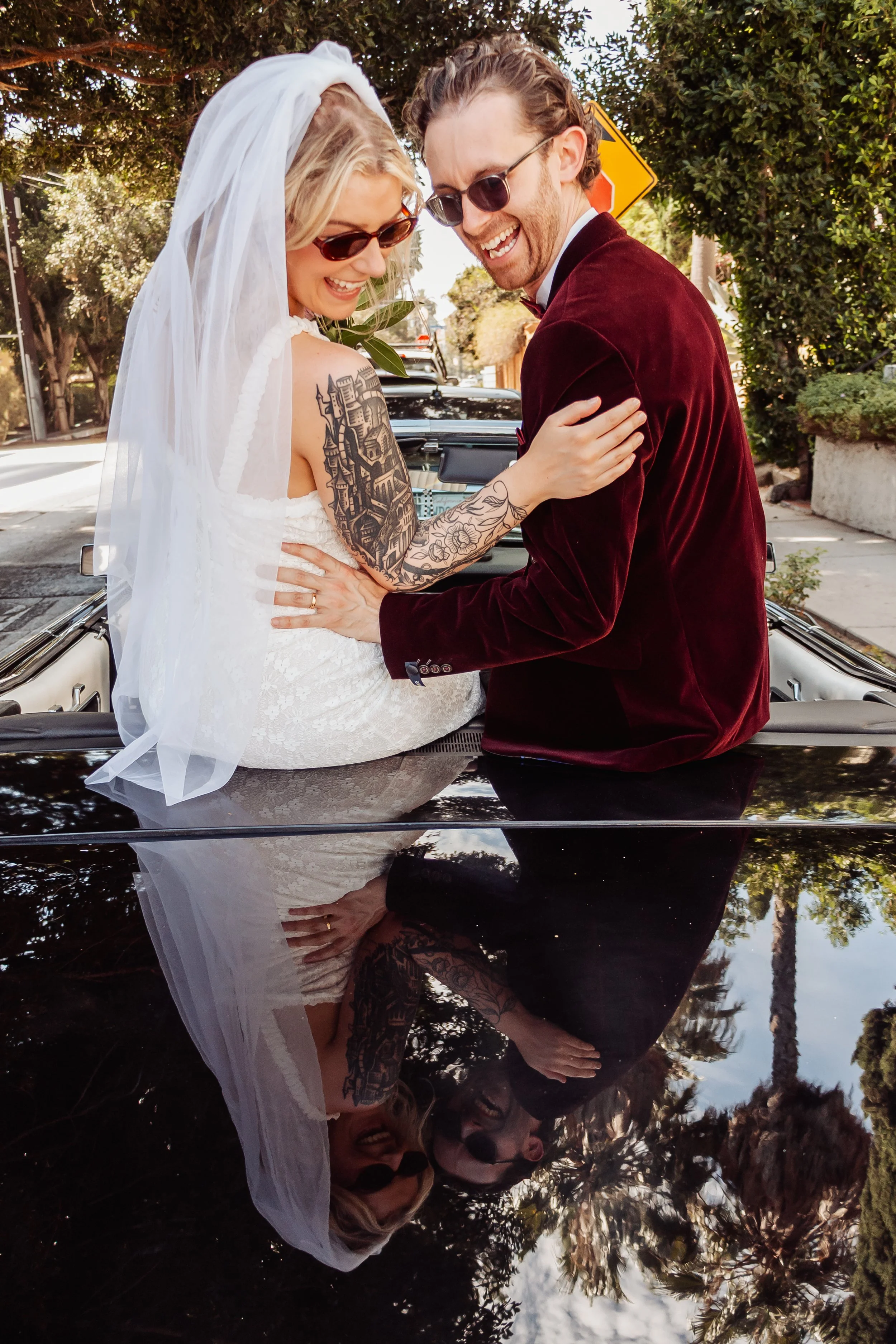 Married couple sitting on top of a vintage car in Hollywood during their Cakewalk elopement.