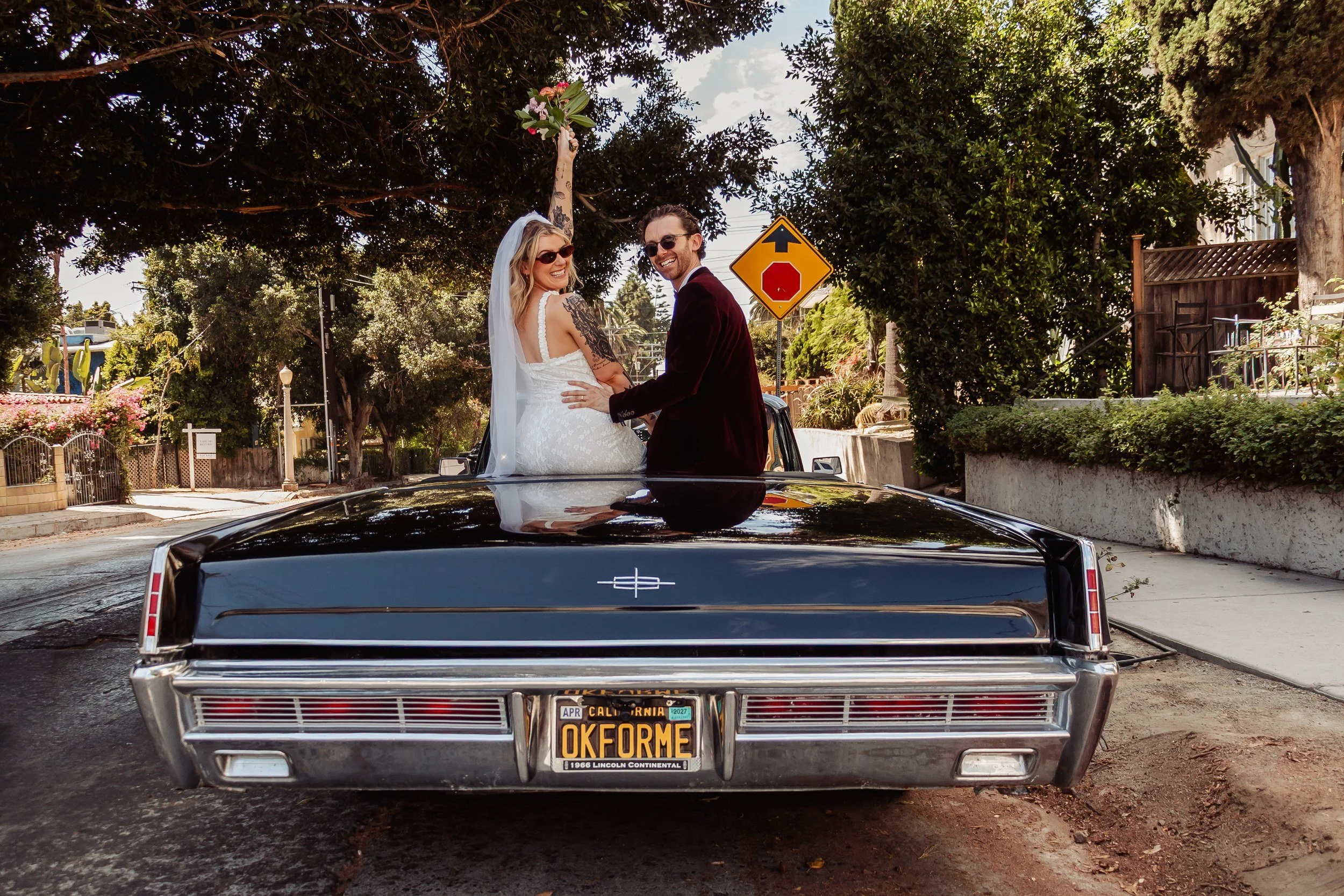 Emma and Adam on the back of a 1966 Lincoln Continental after their Lake Hollywood Park elopement.