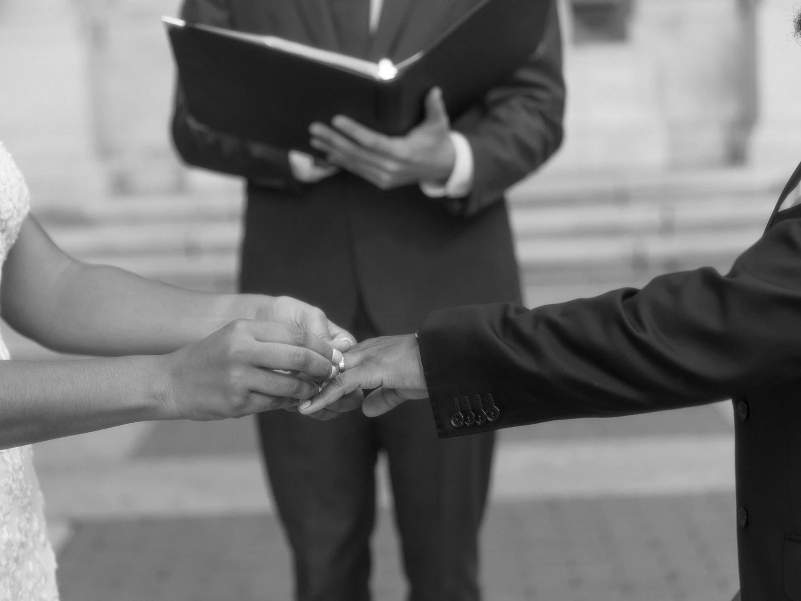 Close up of bride and groom exchanging rings while being married by their Cakewalk officiant at Bryant Park in NYC.