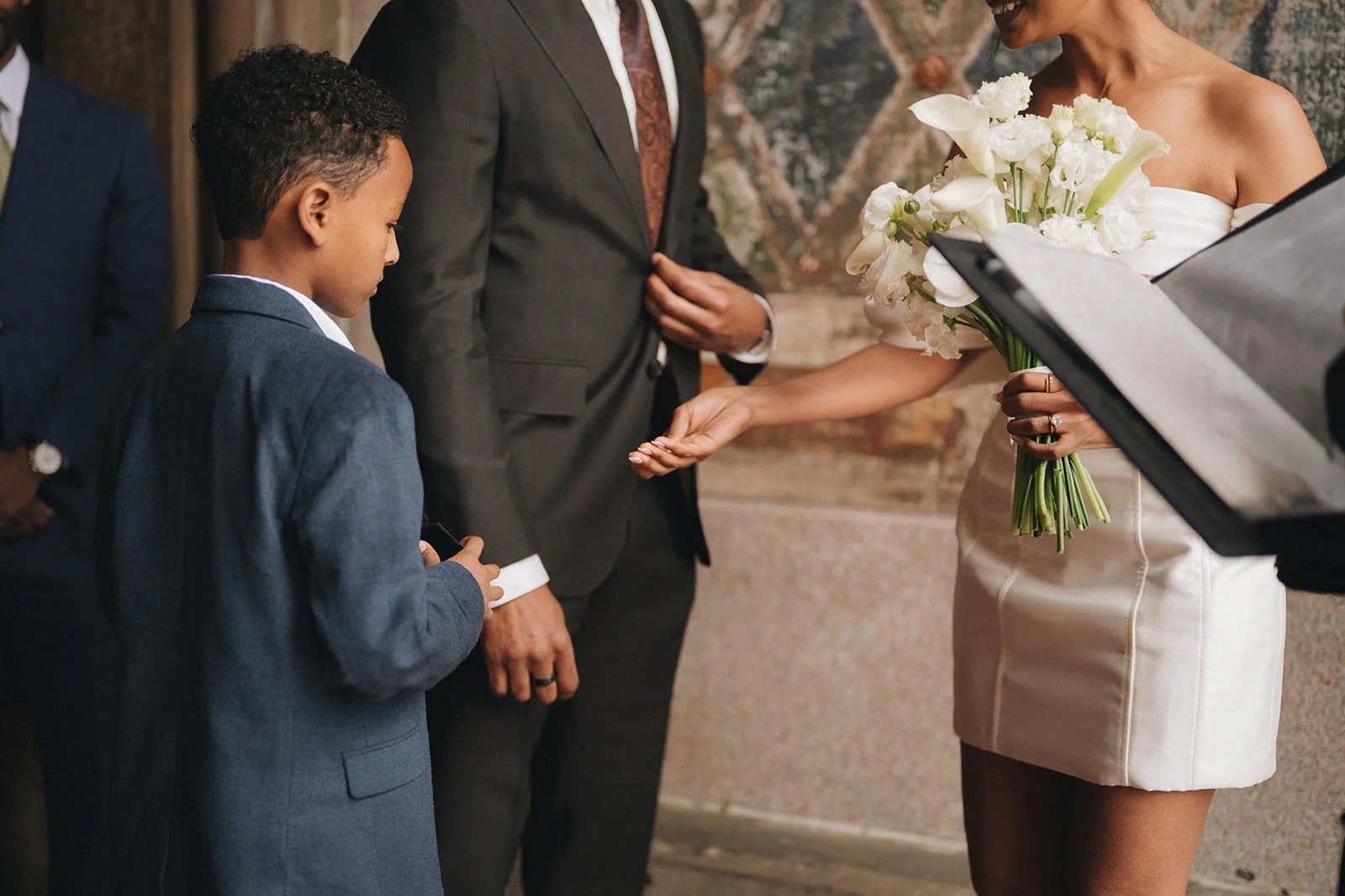 Boy handing bride and groom rings during their Cakewalk micro wedding at Bethesda Terrace.
