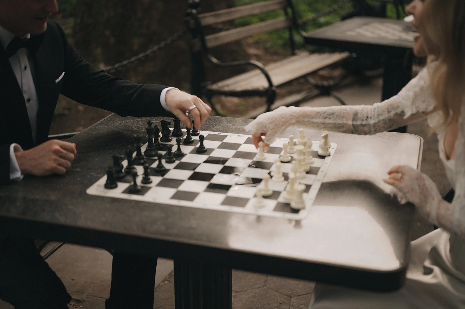 Close up of couple playing chess in their wedding clothes at Washington Square Park.