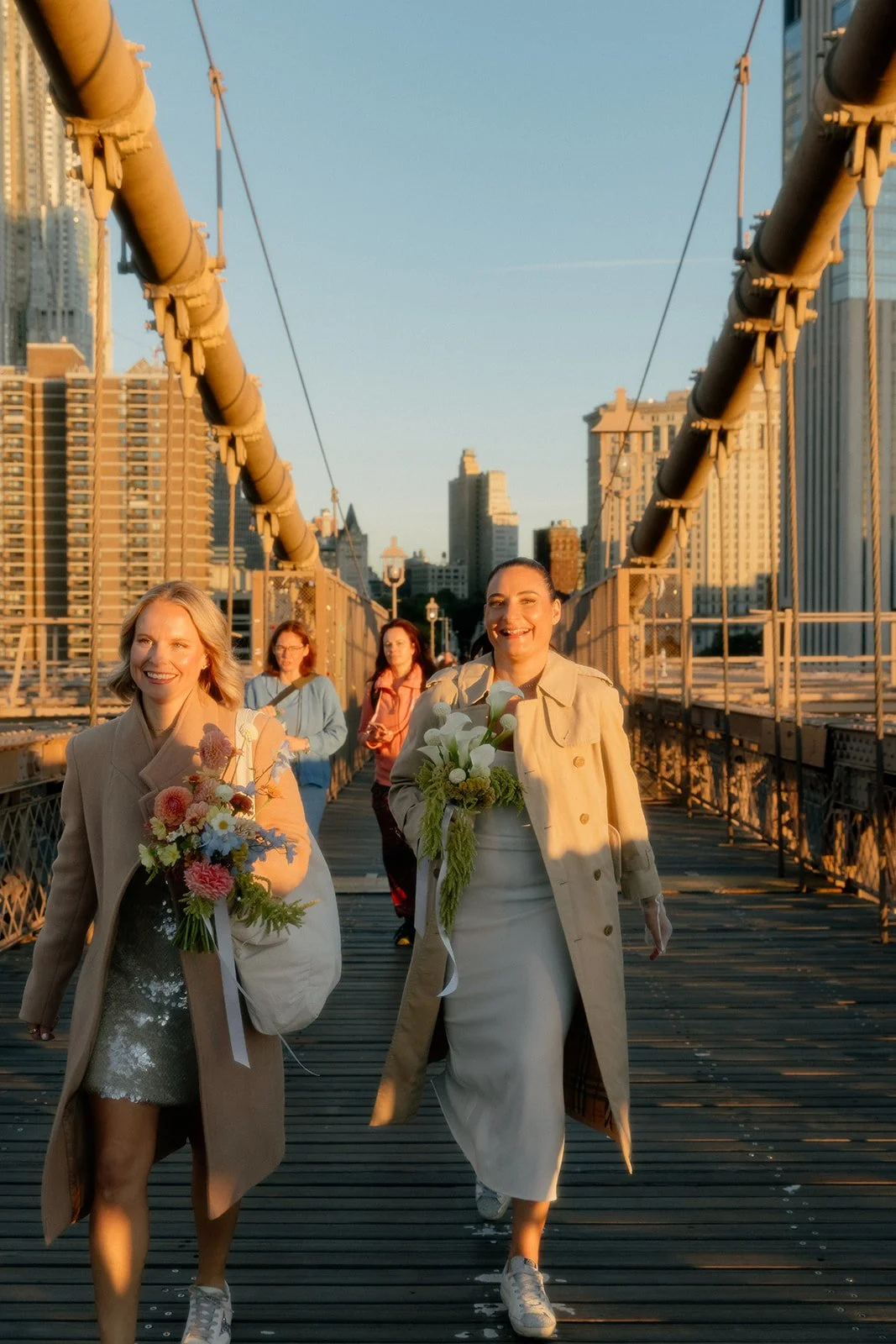 LGBT brides arriving at their Cakewalk micro wedding on the Brooklyn Bridge at sunrise followed by their group of guests.