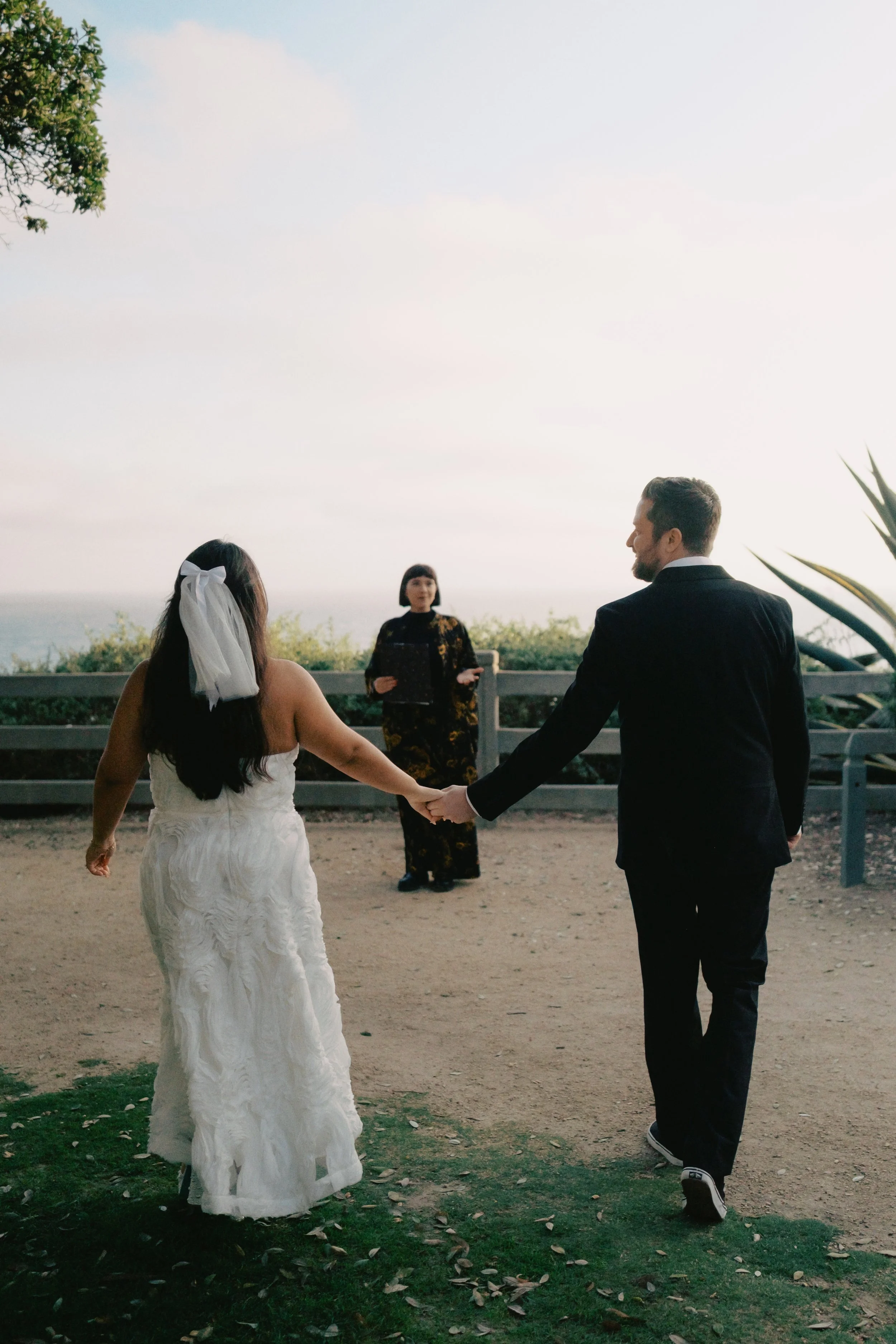 Bride and groom walking towards their officiant at Palisades Park in Santa Monica.