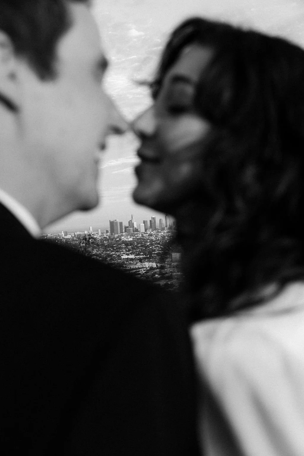 Couple kissing with the Los Angeles downtown skyline in the background, overlooking the LA basin.