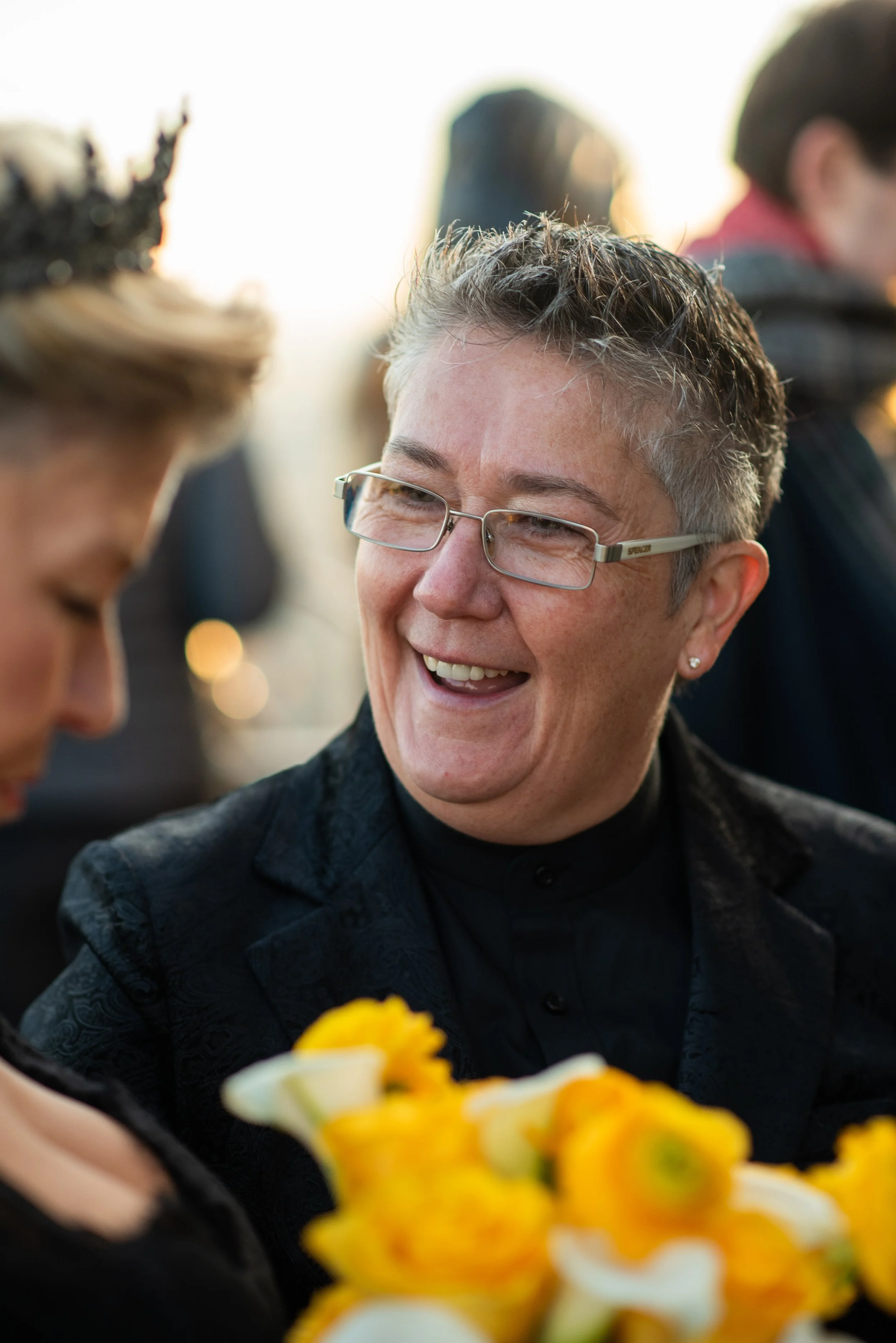 A woman wearing black and glasses smiling at the Top of the Rock after her Cakewalk elopement.