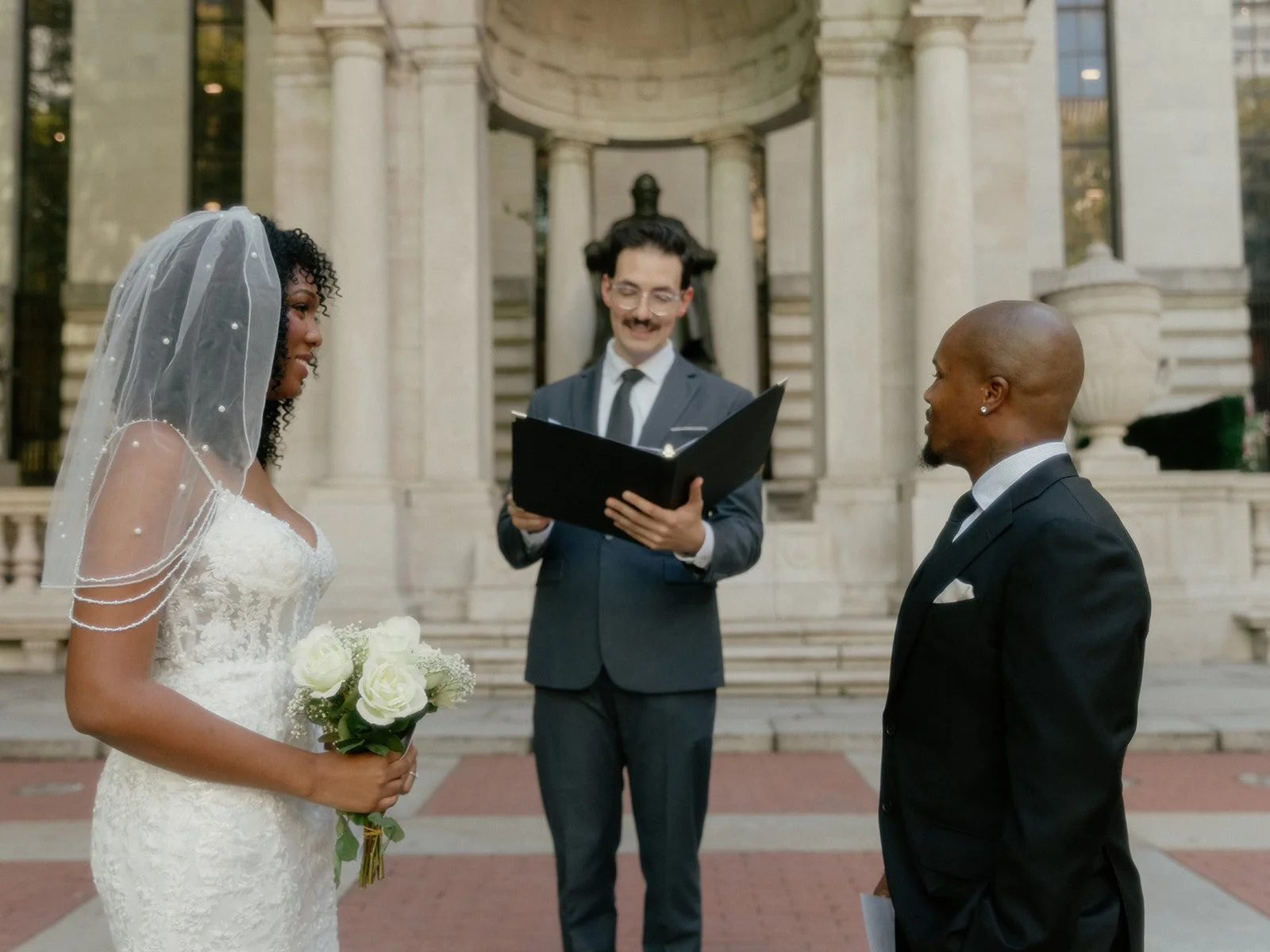 Bride and groom being married by their Cakewalk officiant in front of the statue at Bryant Park in NYC.