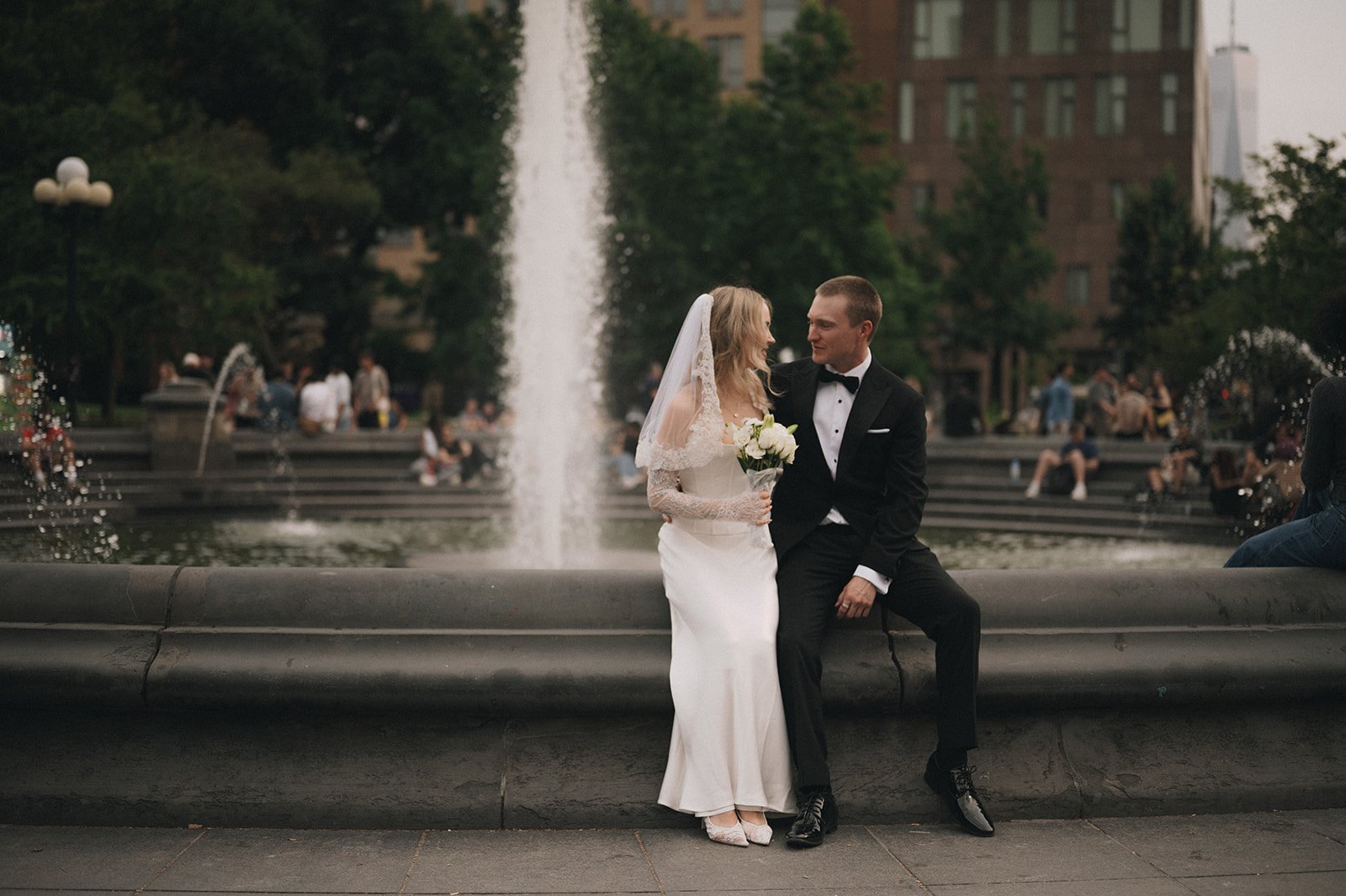 Couple sitting on the fountain at Washington Square Park after their Cakewalk ceremony.