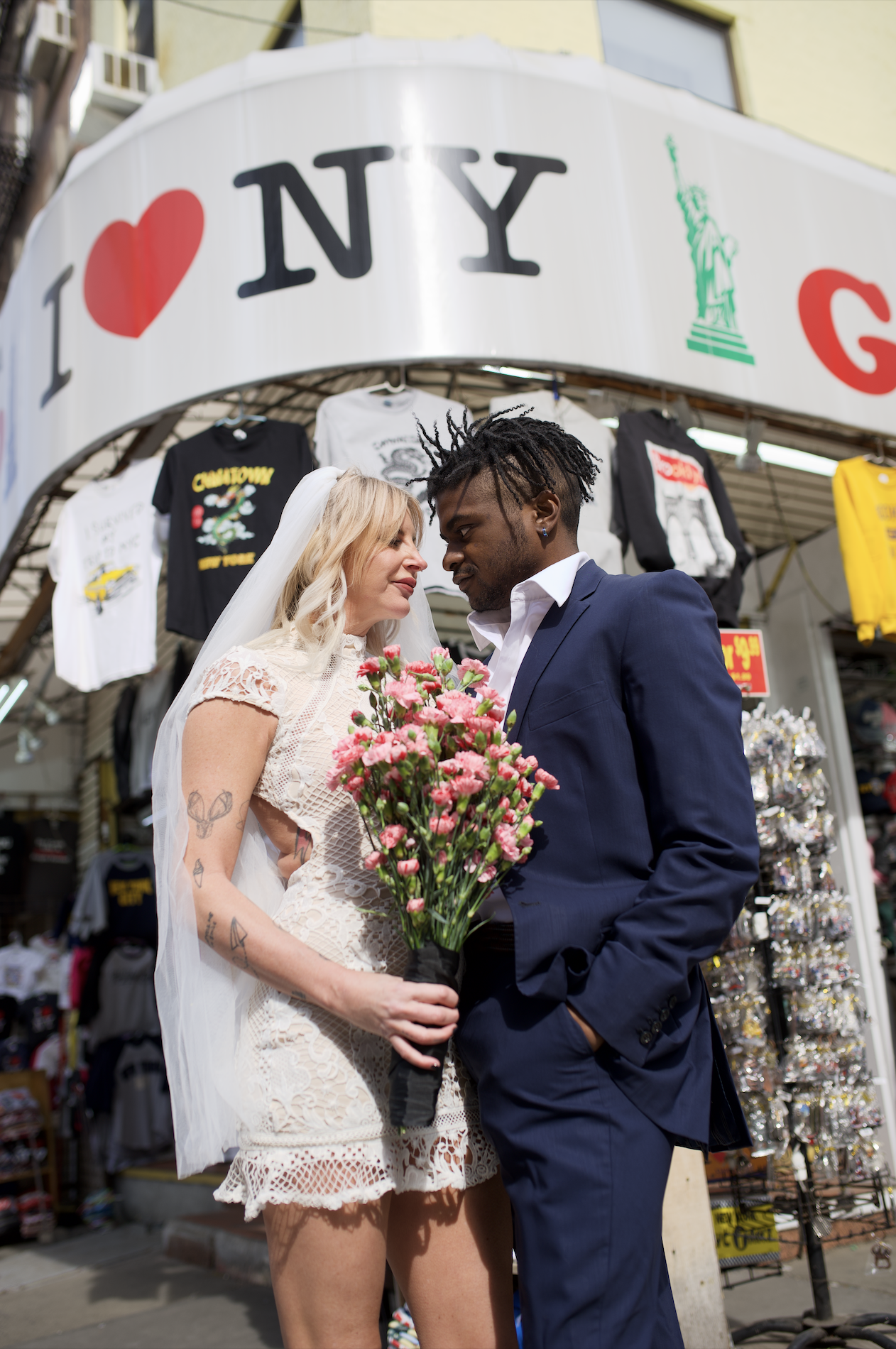 Bride and groom standing in front of a bodega that reads "I Love NY" while walking into Chinatown for their Cakewalk elopement.