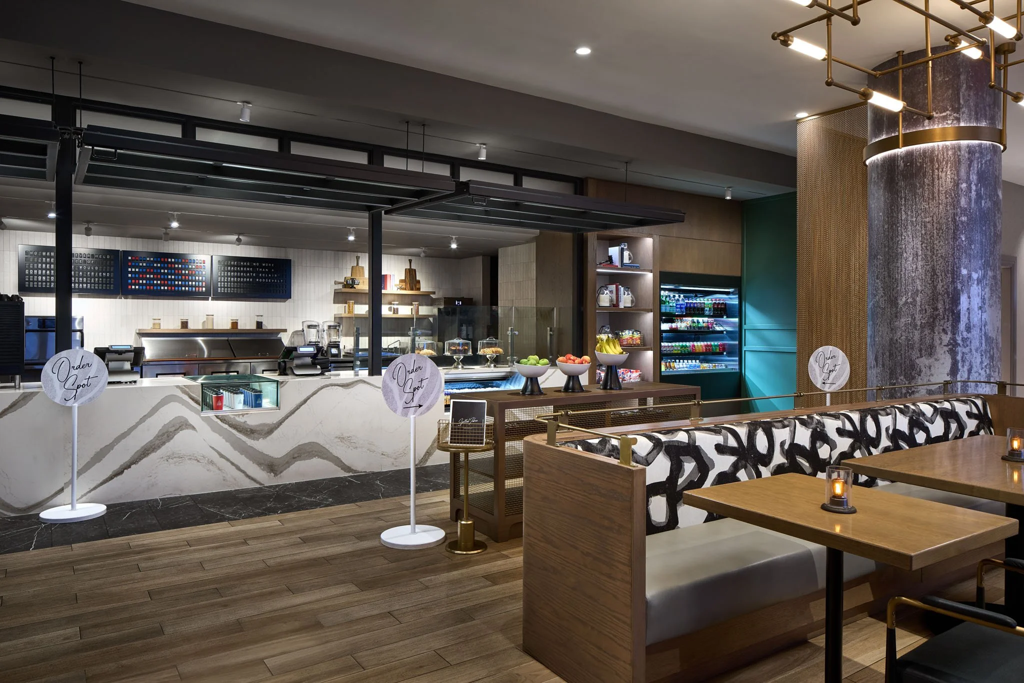 Modern indoor cafe or restaurant with a beverage counter, fruit displays, and seating area with tables, chairs, and candles