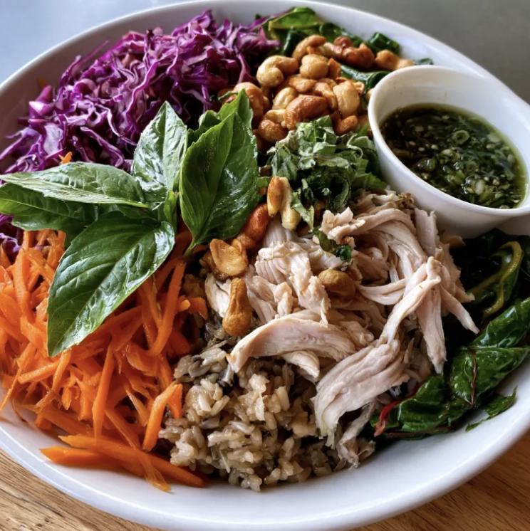 Hanoi Nourish Bowl with Lemongrass & Turmeric Shredded Chicken, Brown Rice, Carrots, Red Cabbage, Swiss Chard, Thai Basil, Cashews, Charred Scallion & Lemongrass Sauce