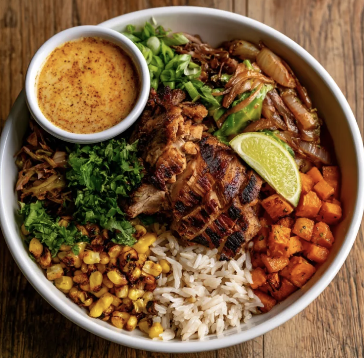 Caribbean Nourish Bowl with Jerk Chicken, Coconut Basmati Rice, Braised Cabbage, Caramelized Onions, Carrots, Corn, Cilantro, Scallions, Lime, Coconut Pineapple Lime Sauce