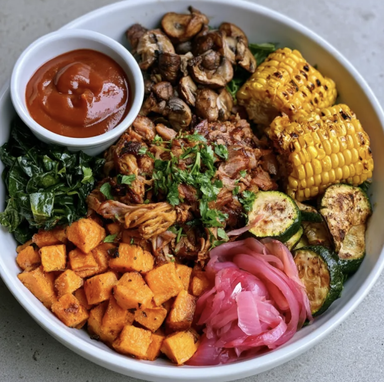 Southern Smoke Bowl with BBQ Shredded Pork, Sweet Potato, Zucchini, Braised Collard Greens, Mushrooms, Grilled Corn, Pickled Shallots, Parsley, Smoky Peach BBQ Sauce