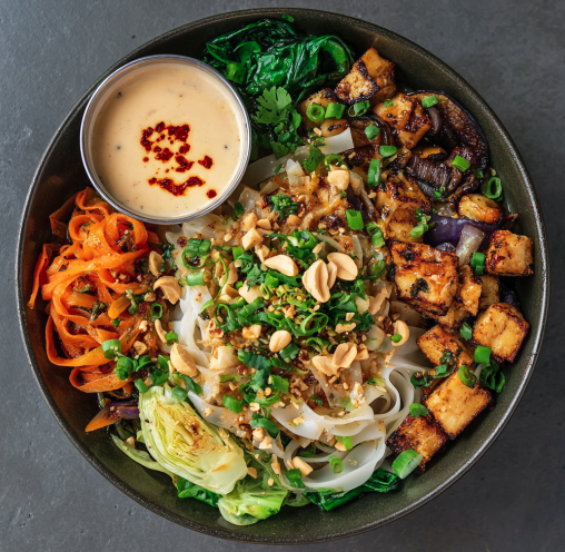 Balance & Bloom Bowl with Citrus Tofu, Brown Rice Noodles, Roasted Eggplant, Bok Choy, Carrots, Napa Cabbage, Scallions, Peanuts, Cilantro, and a Creamy Sesame Sauce, Chili Oil Drizzle