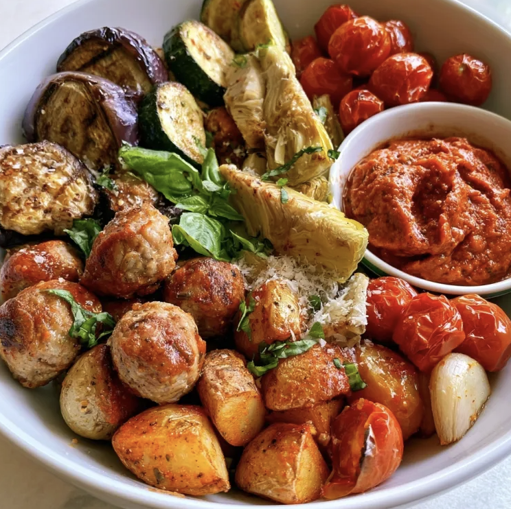 Mediterranean Protein Bowl with Summer Pork Meatballs, Baby Potatoes, Eggplant, Zucchini, Cherry Tomatoes, Artichoke Heart, Roasted Garlic, Basil, Parm, Roasted Almond Pepper Romesco