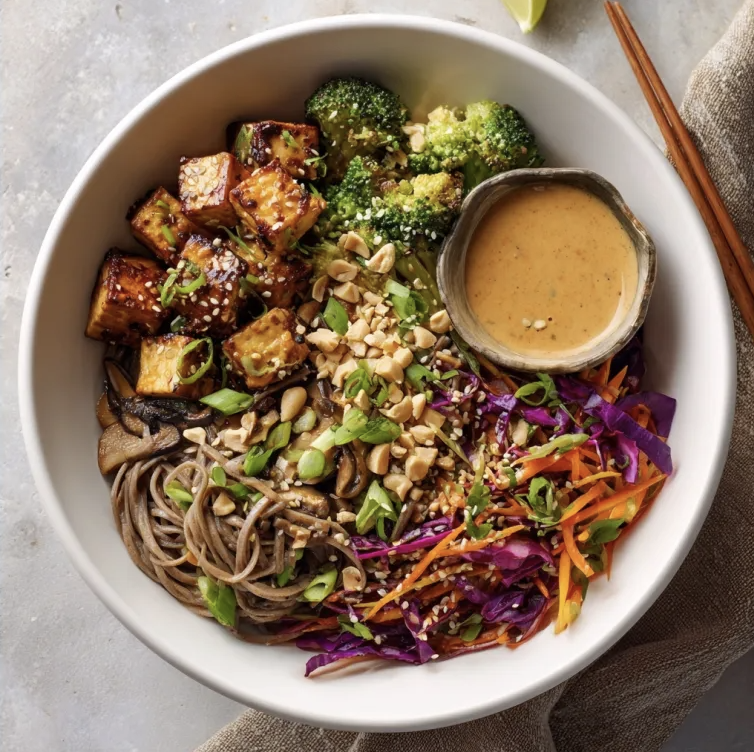 Sesame Peanut Bowl with Smoky Sesame Tofu, Soba Noodles, Broccoli, Mushrooms, Sesame Carrot & Red Cabbage Slaw, Peanuts, Scallions, Chili Lime Peanut Sauce