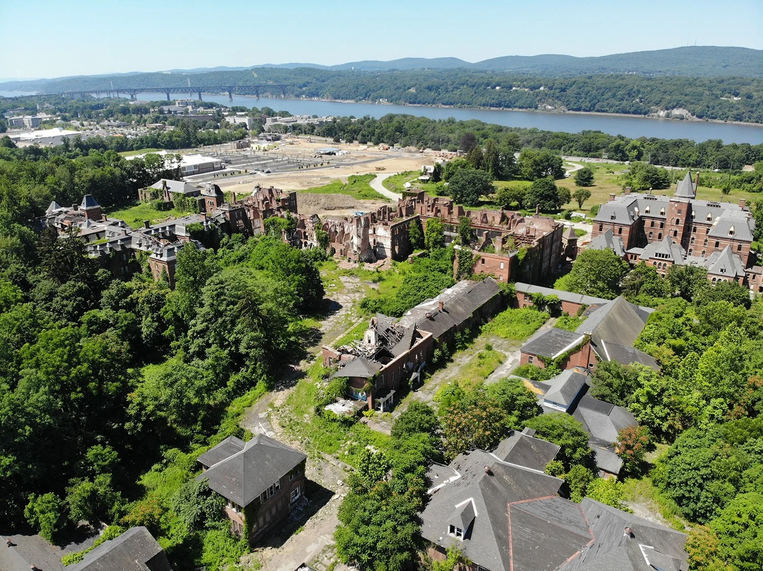 Aerial view of a historic, abandoned brick asylum sitting on acres of Brownfield.
