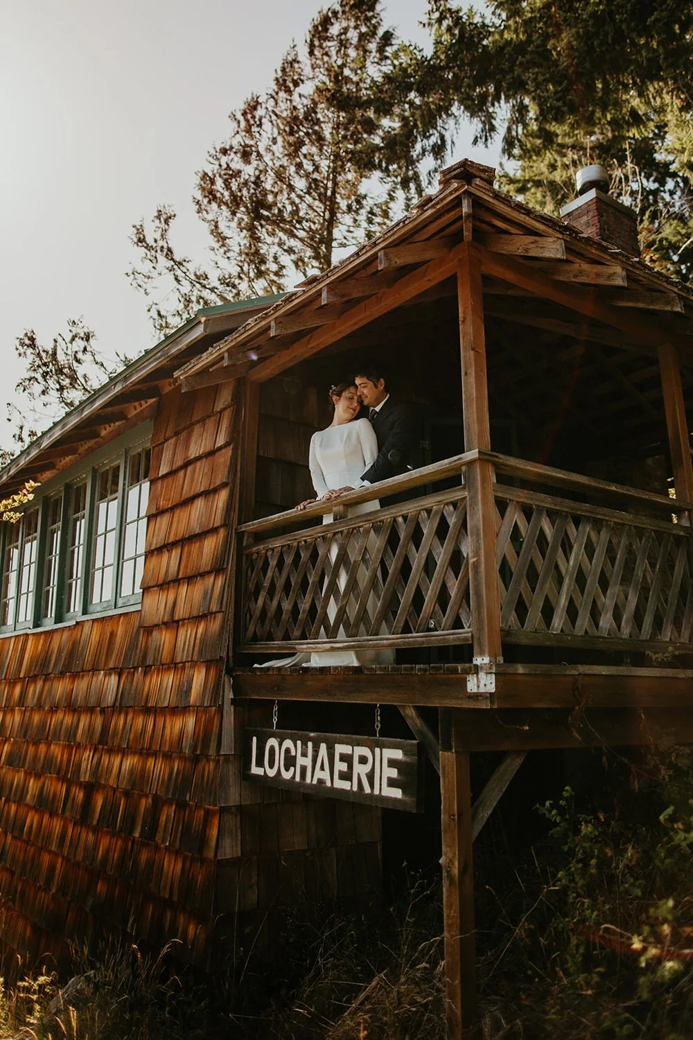 Couple embracing on the wooden porch of Lochaerie Resort on the Olympic Peninsula during their Washington elopement
