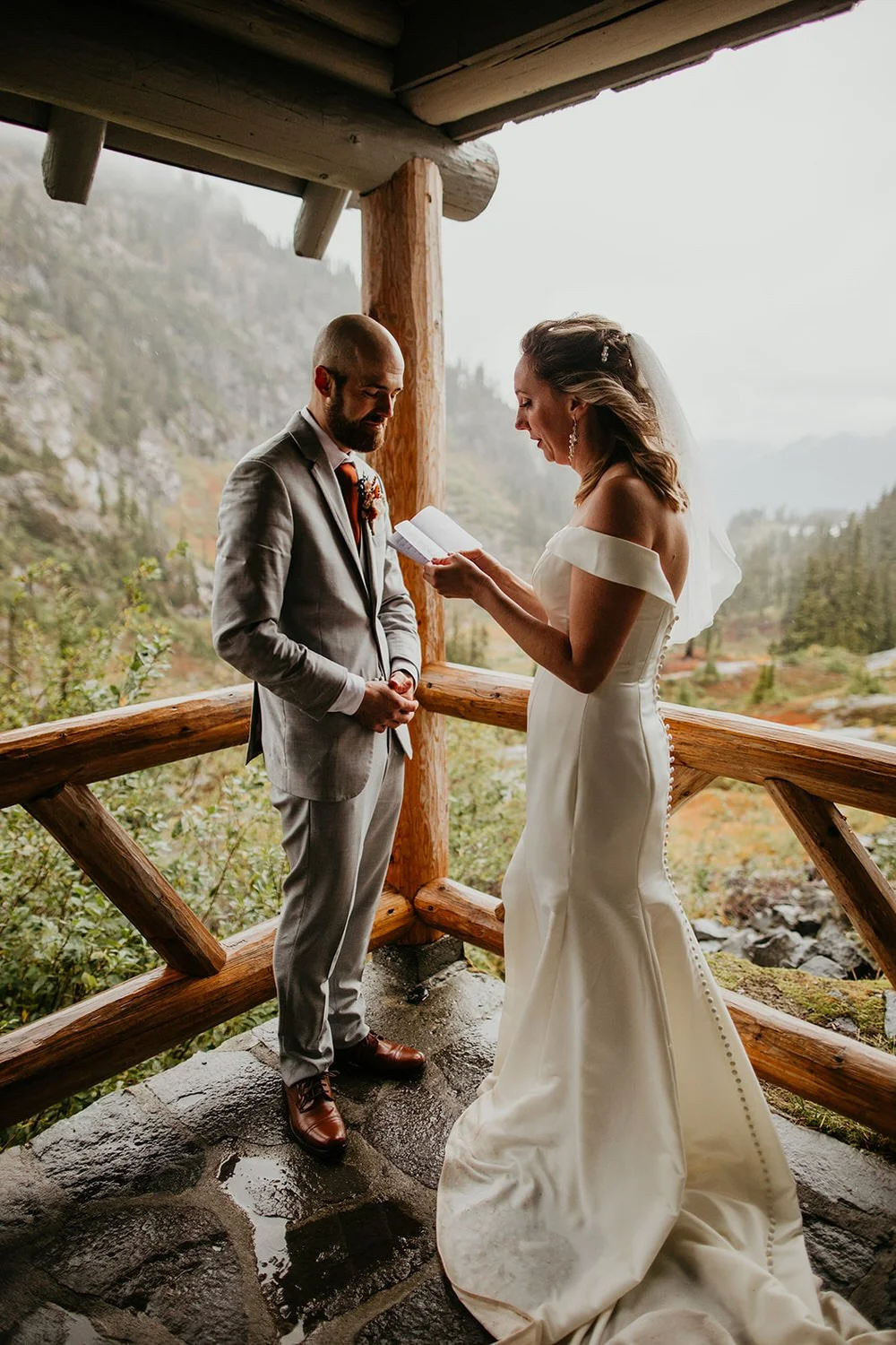 Bride reading private vows under the covered porch of the Heather Meadows Visitor Center in the rain