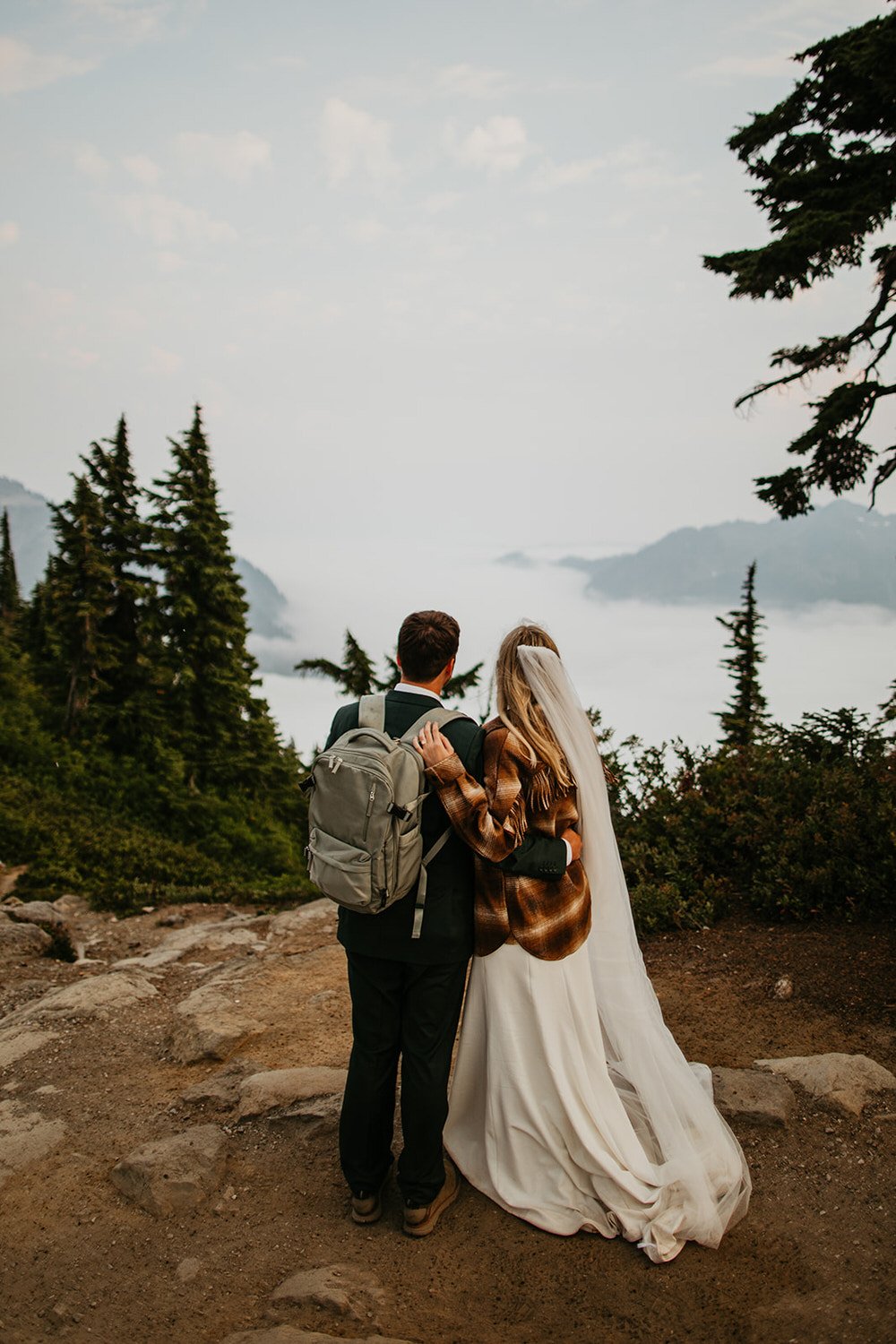 Couple holding hands as they take in a sunset cloud inversion with Mount Shuksan emerging above the fog