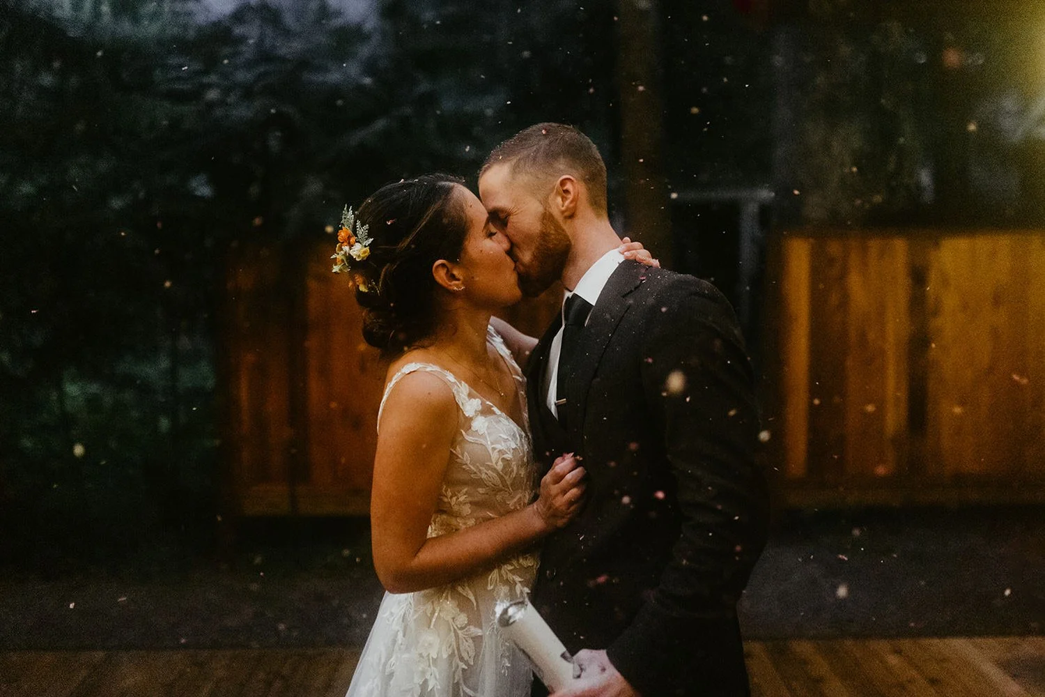 Bride and groom kiss while confetti falls around them on a cabin deck