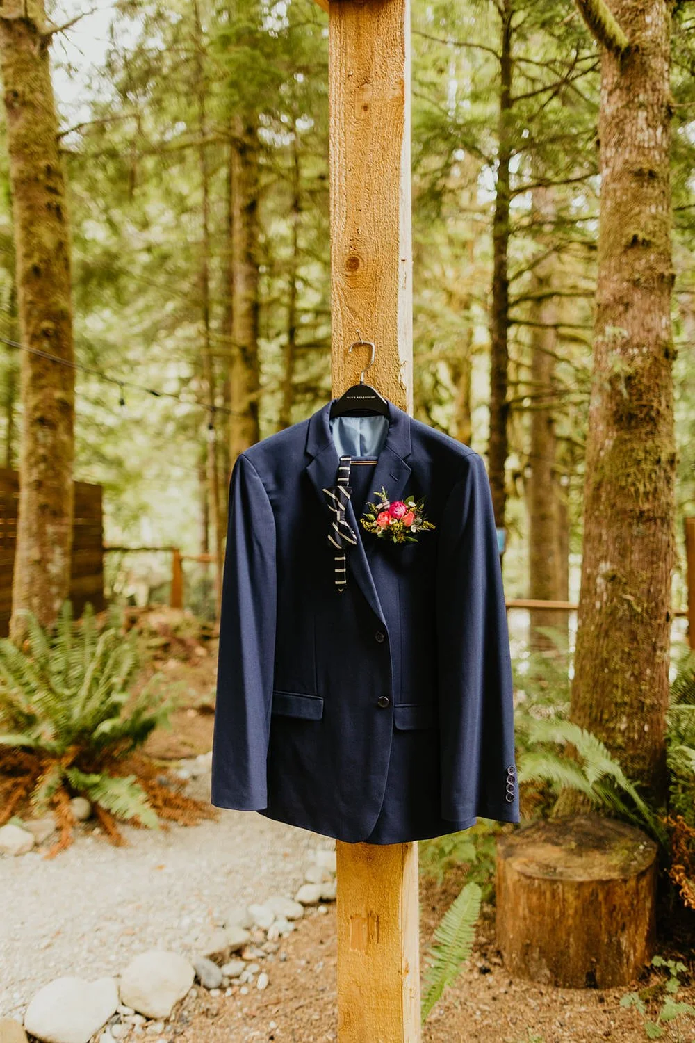 Navy suit jacket hanging on a wooden hanger inside a cabin on elopement day
