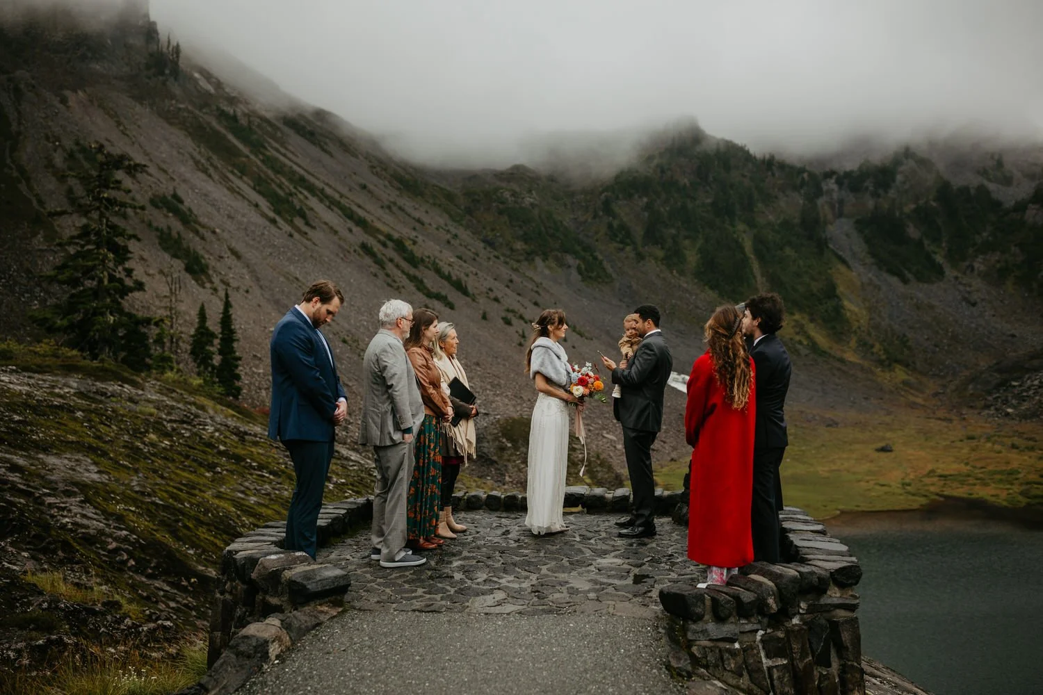 Family ceremony on a stone overlook platform with fog rolling over the surrounding peaks