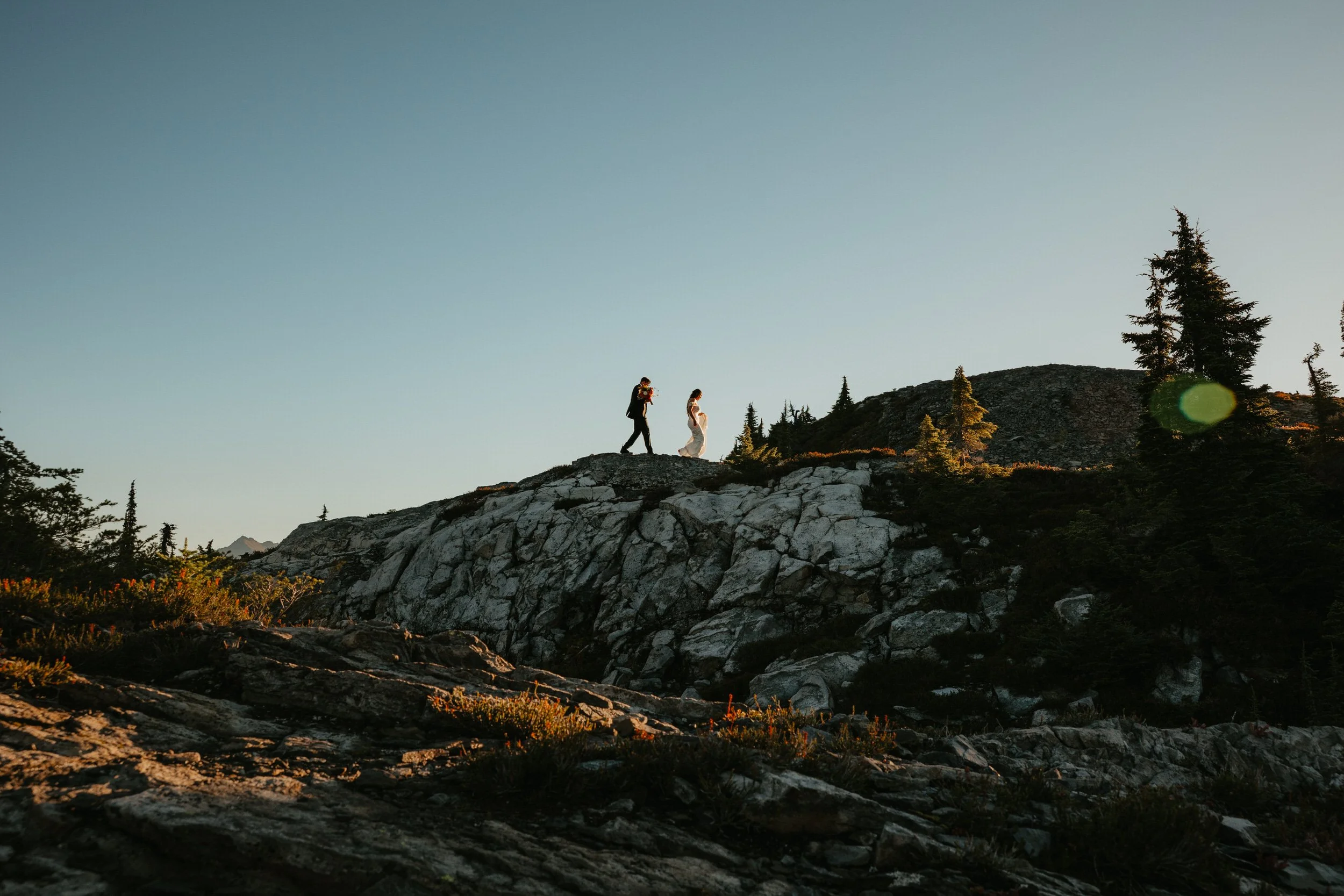 Couple hiking together along a rocky mountain ridge during their elopement day