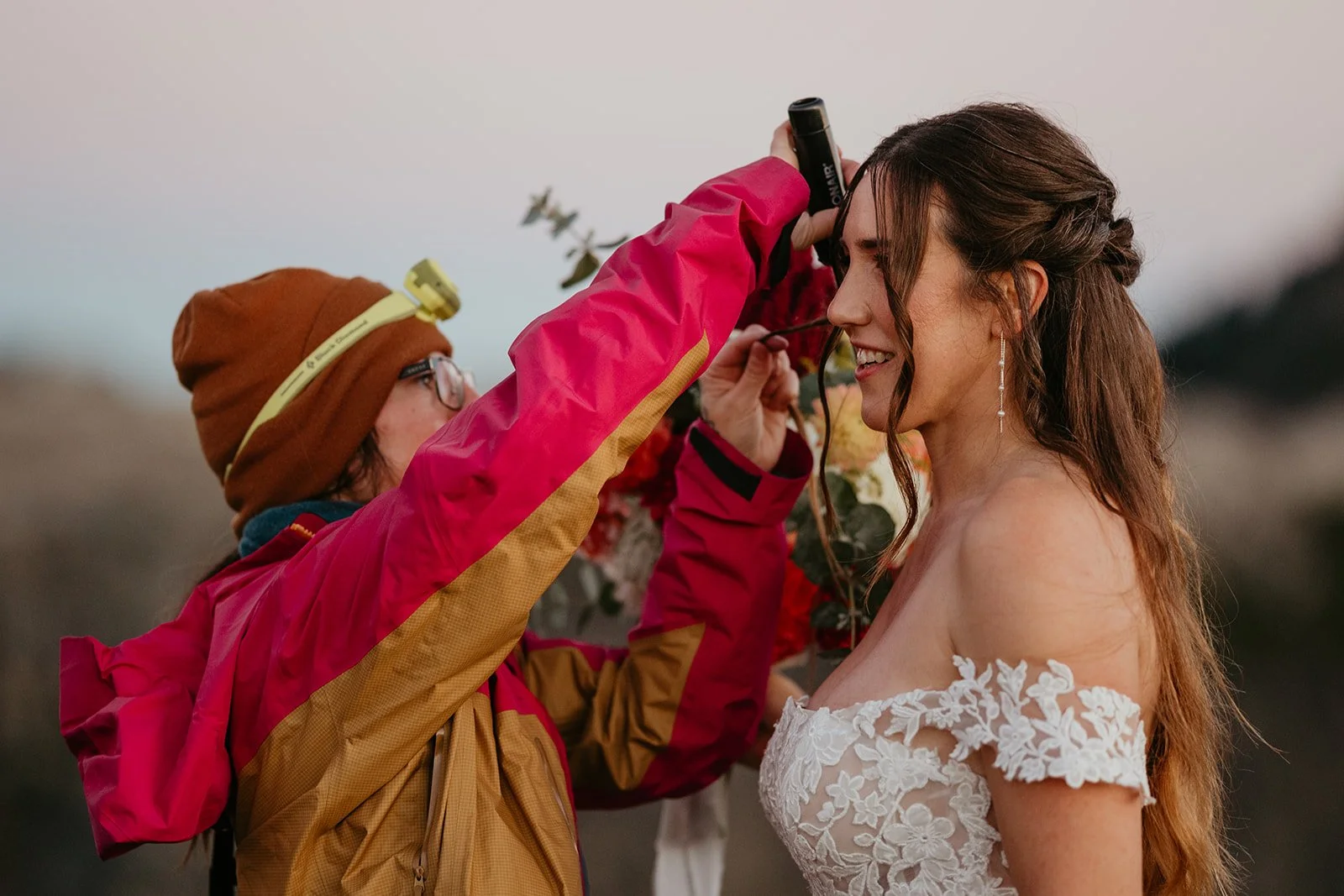 Hair and makeup artist touching up the bride's look outdoors just before her ceremony