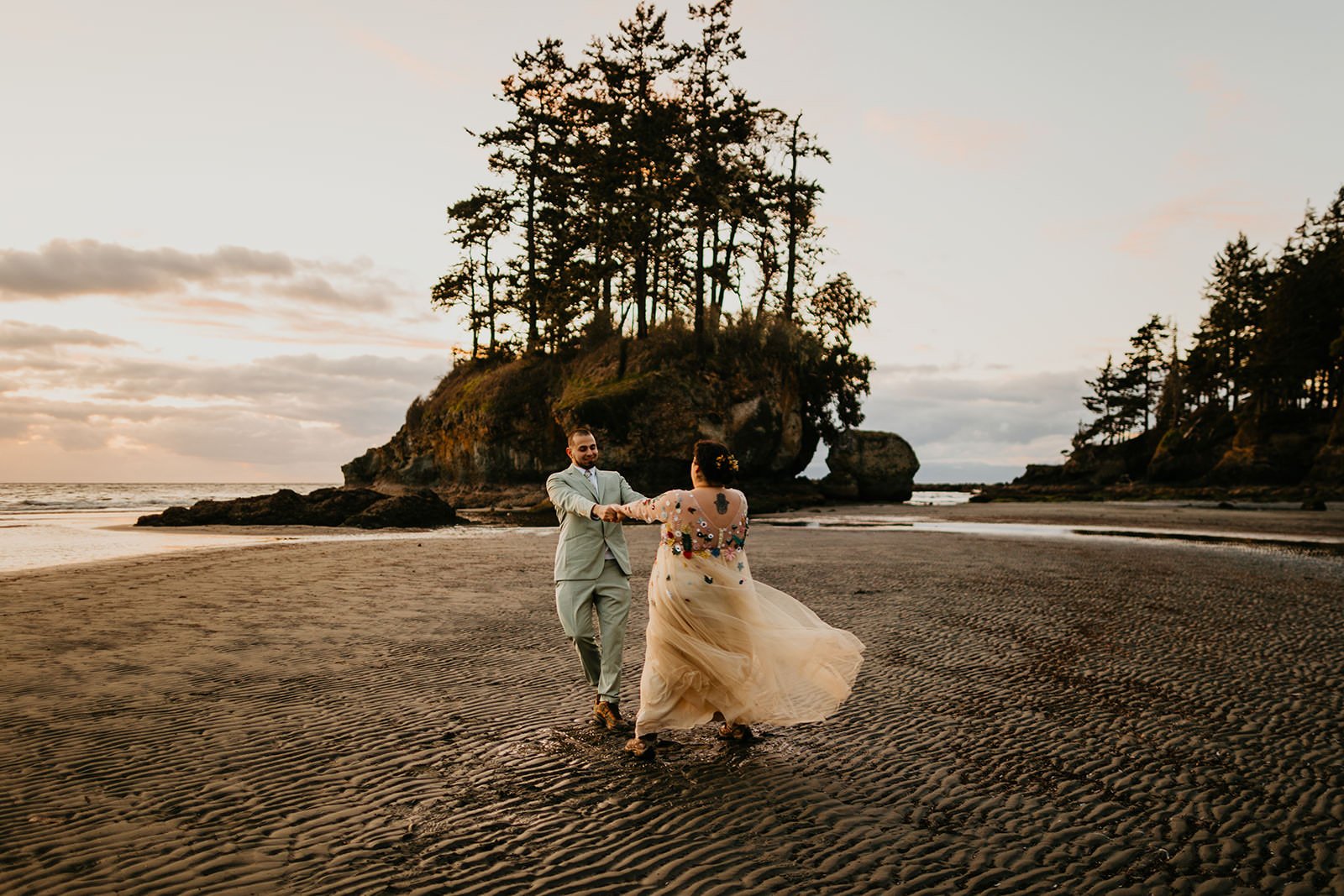 Couple walking along a foggy Washington coastline with waves, sea stacks, and dramatic skies