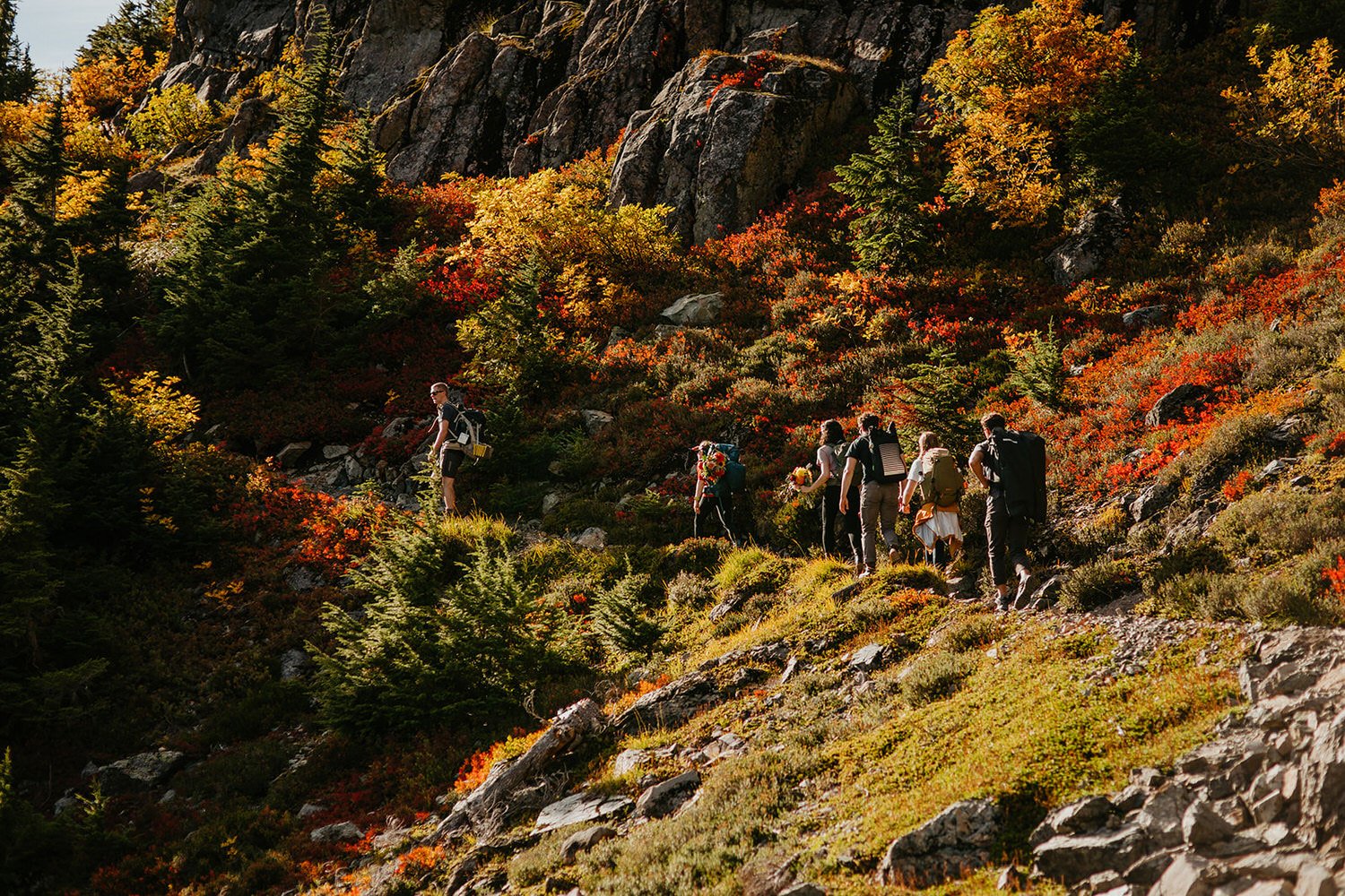 Couple hiking through fall foliage in the North Cascades, following Leave No Trace principles on a narrow alpine trail