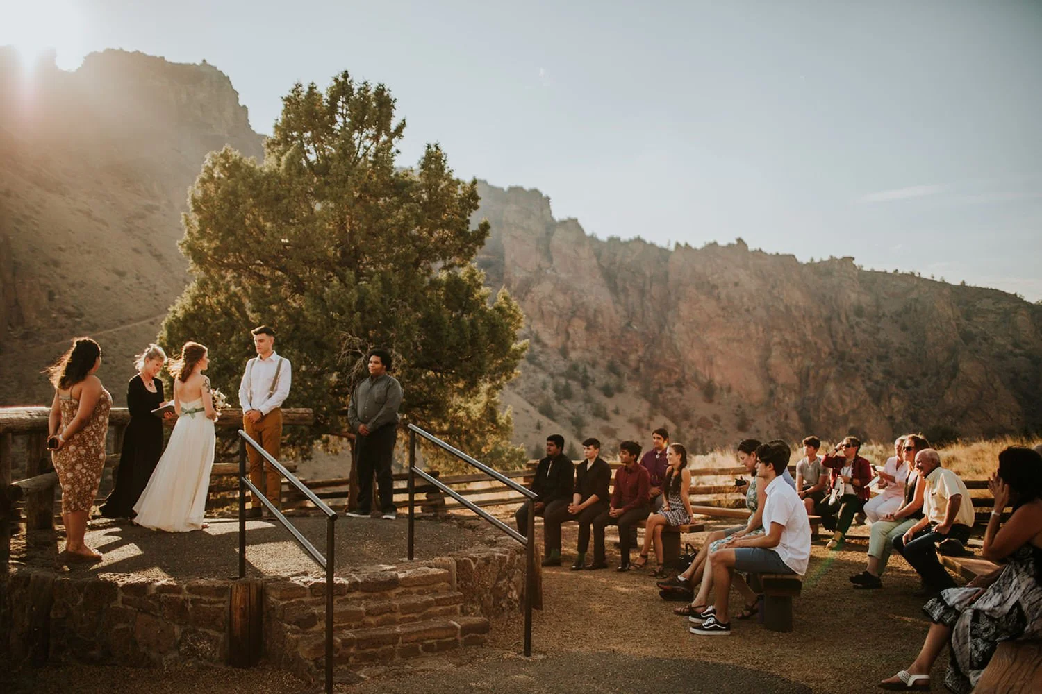 Outdoor elopement ceremony with guests seated at a scenic overlook in a canyon landscape