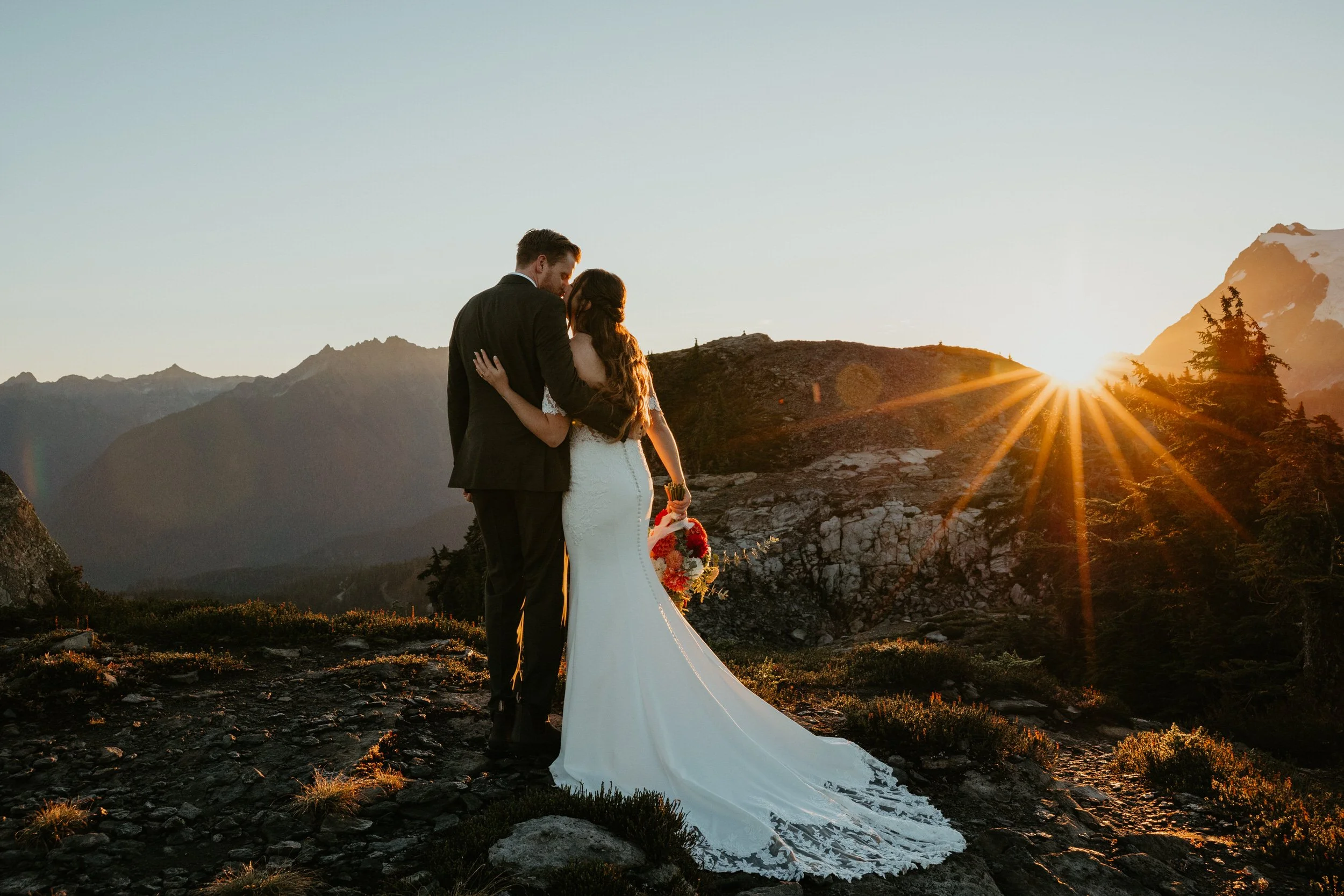 Couple standing together at sunrise overlooking mountain ridgelines during their elopement