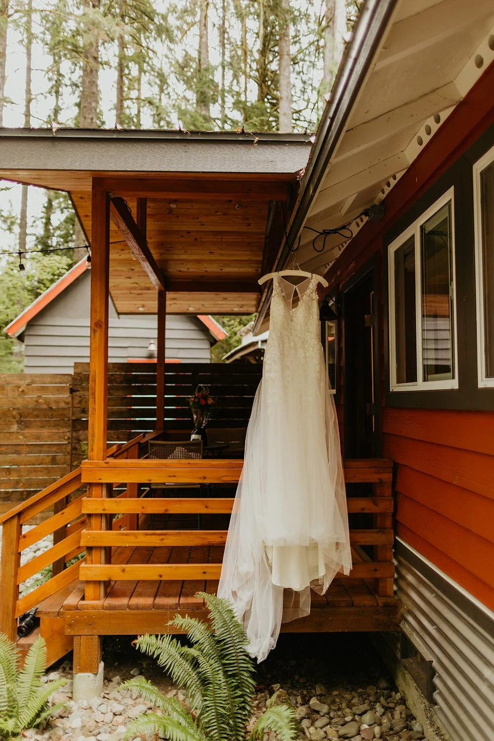 White wedding dress draped over wooden cabin stairs, soft natural light filtering in
