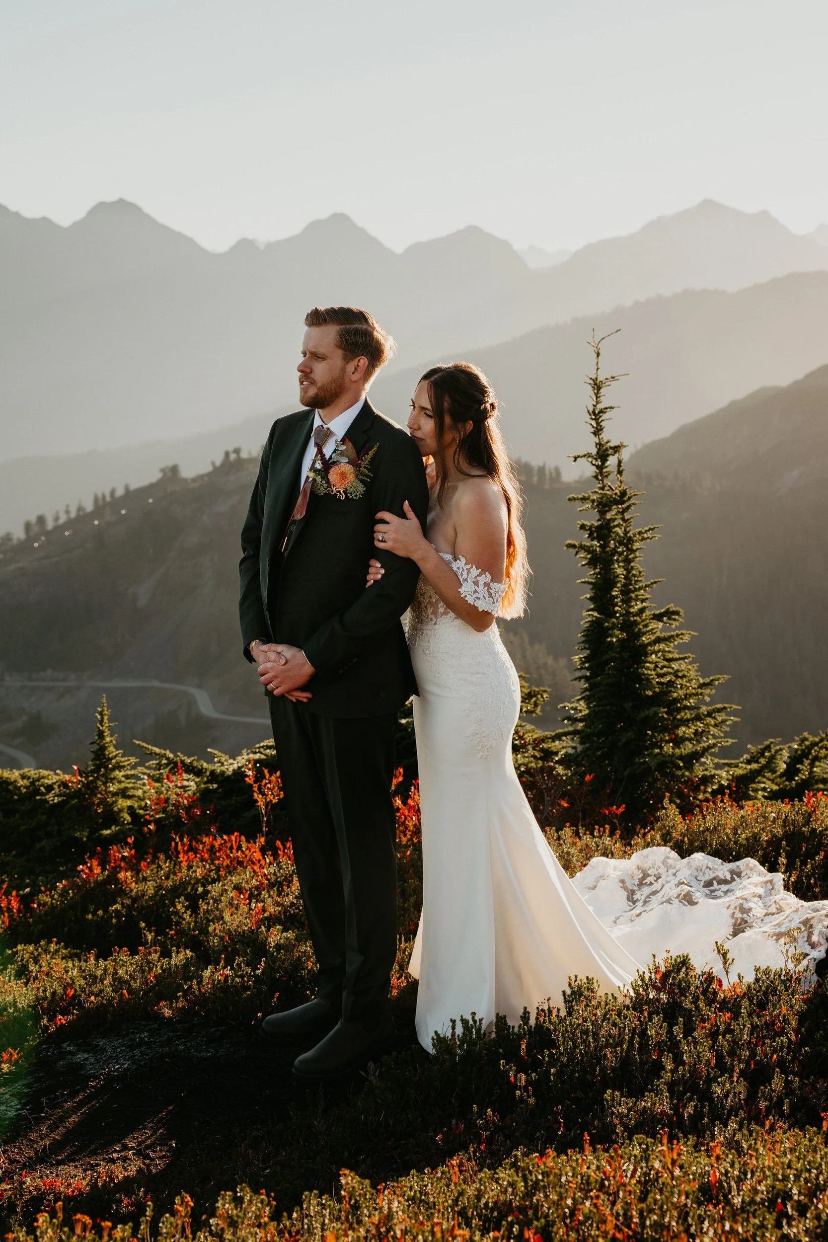 Couple standing together on a mountain ridge surrounded by fall colors at sunrise